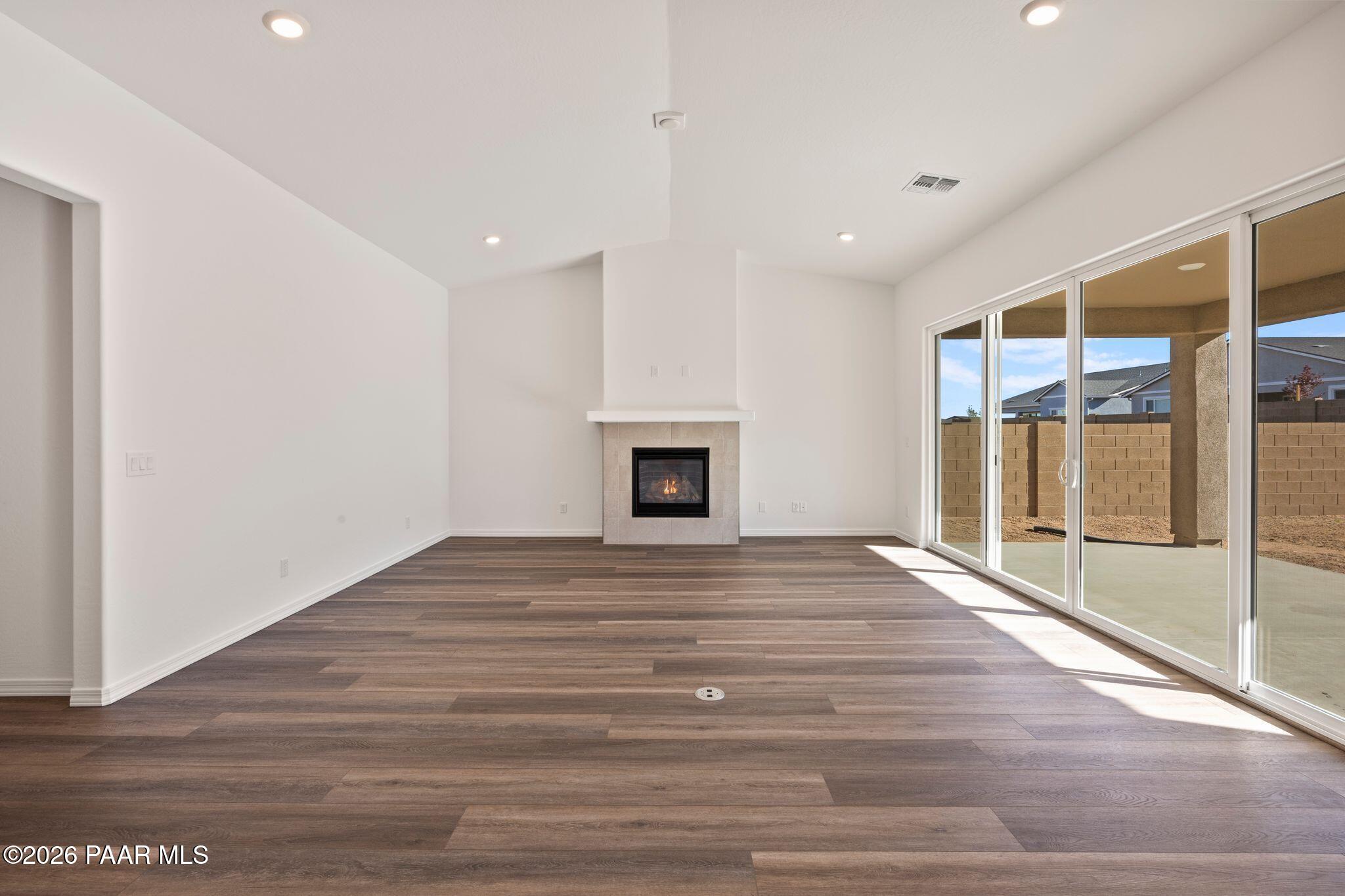 Spacious living room with modern stone fireplace, sliding glass doors to backyard, and hardwood floors in Davidson Homes Sunrise II A, Prescott AZ