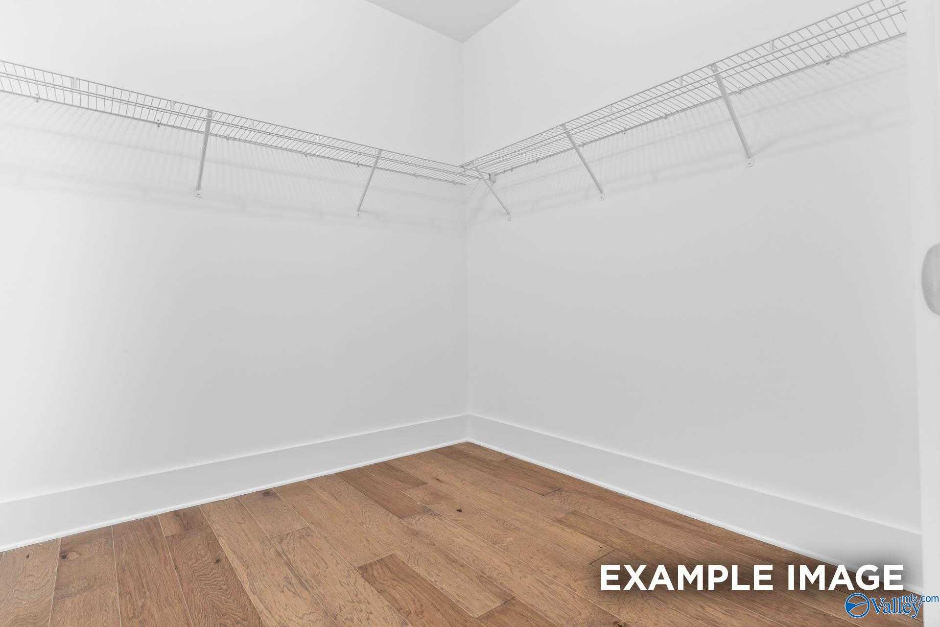 Spacious walk-in closet with wire shelving, hanging rods, and hardwood floors in Davidson Homes The Rockford, Meridianville, Alabama