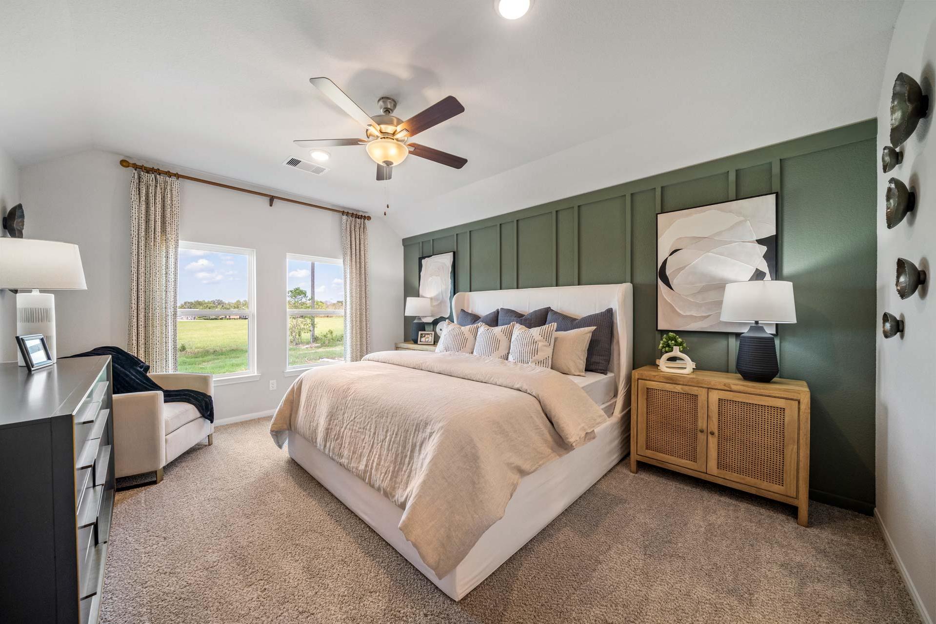 Spacious master bedroom at Windmill Estates in Magnolia Texas with green accent wall, king bed, and rural field views