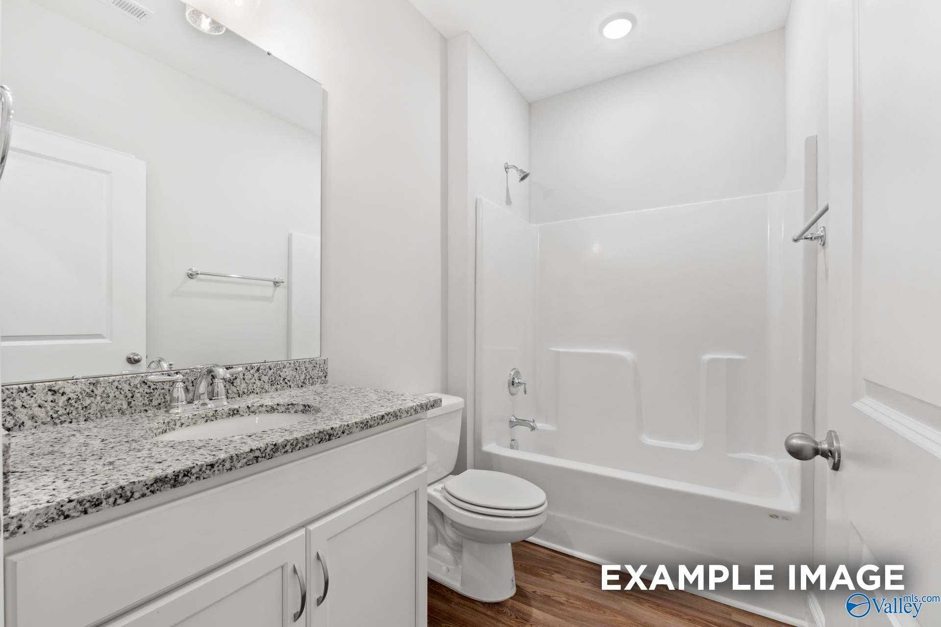 Modern bathroom featuring granite countertop vanity, white subway tile tub-shower combo in Davidson Homes The Cumberland, Decatur, AL