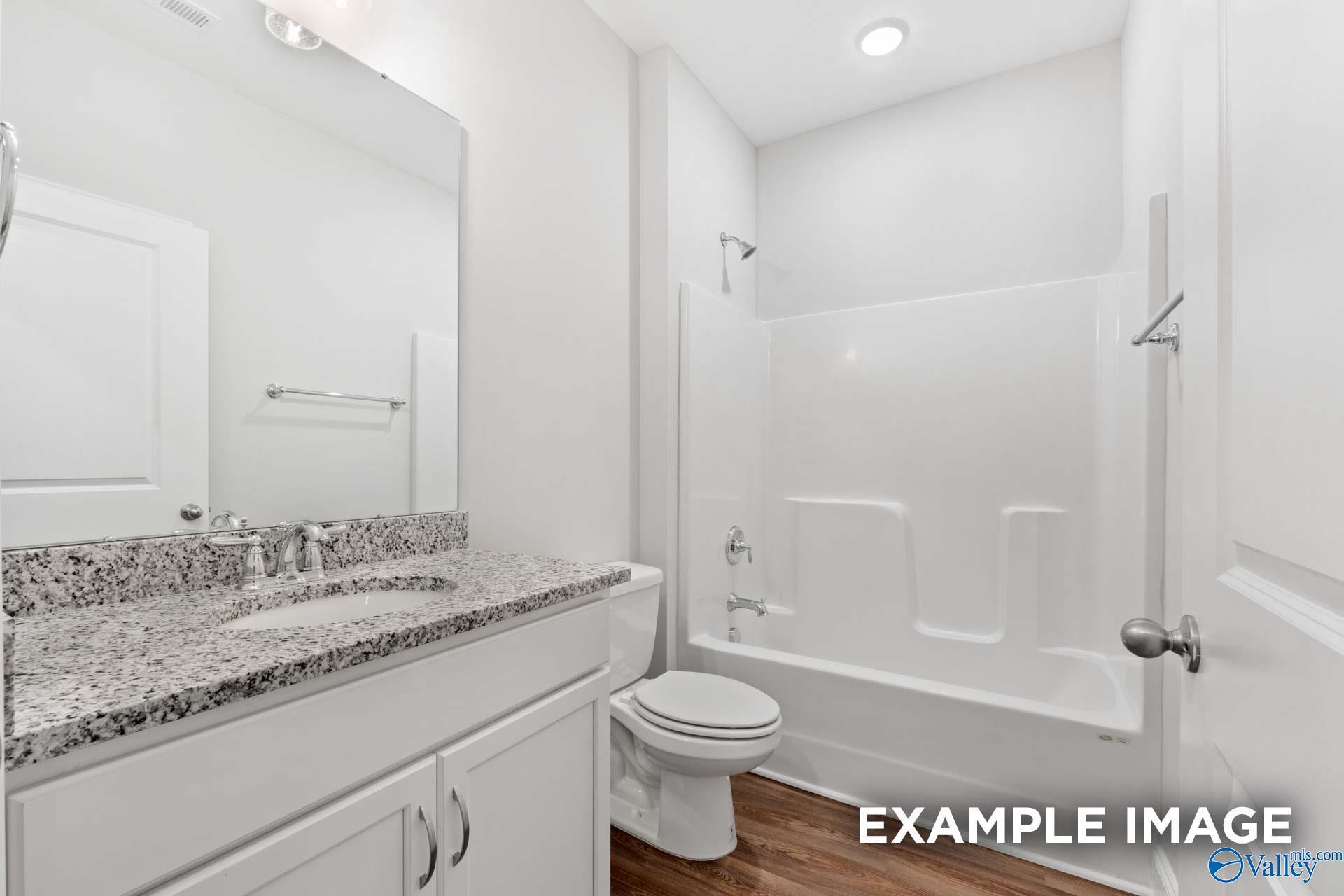Bright bathroom with granite vanity, tub-shower combo, and white tiles in Davidson Homes The Cumberland, Decatur, Alabama