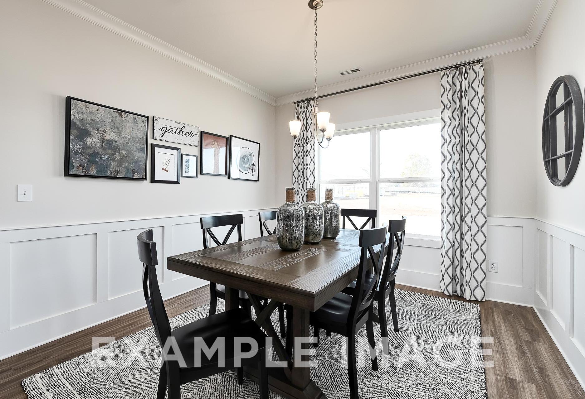Spacious dining room in The Everett B Davidson Homes design featuring wooden table, upholstered chairs, chandelier, and wall art