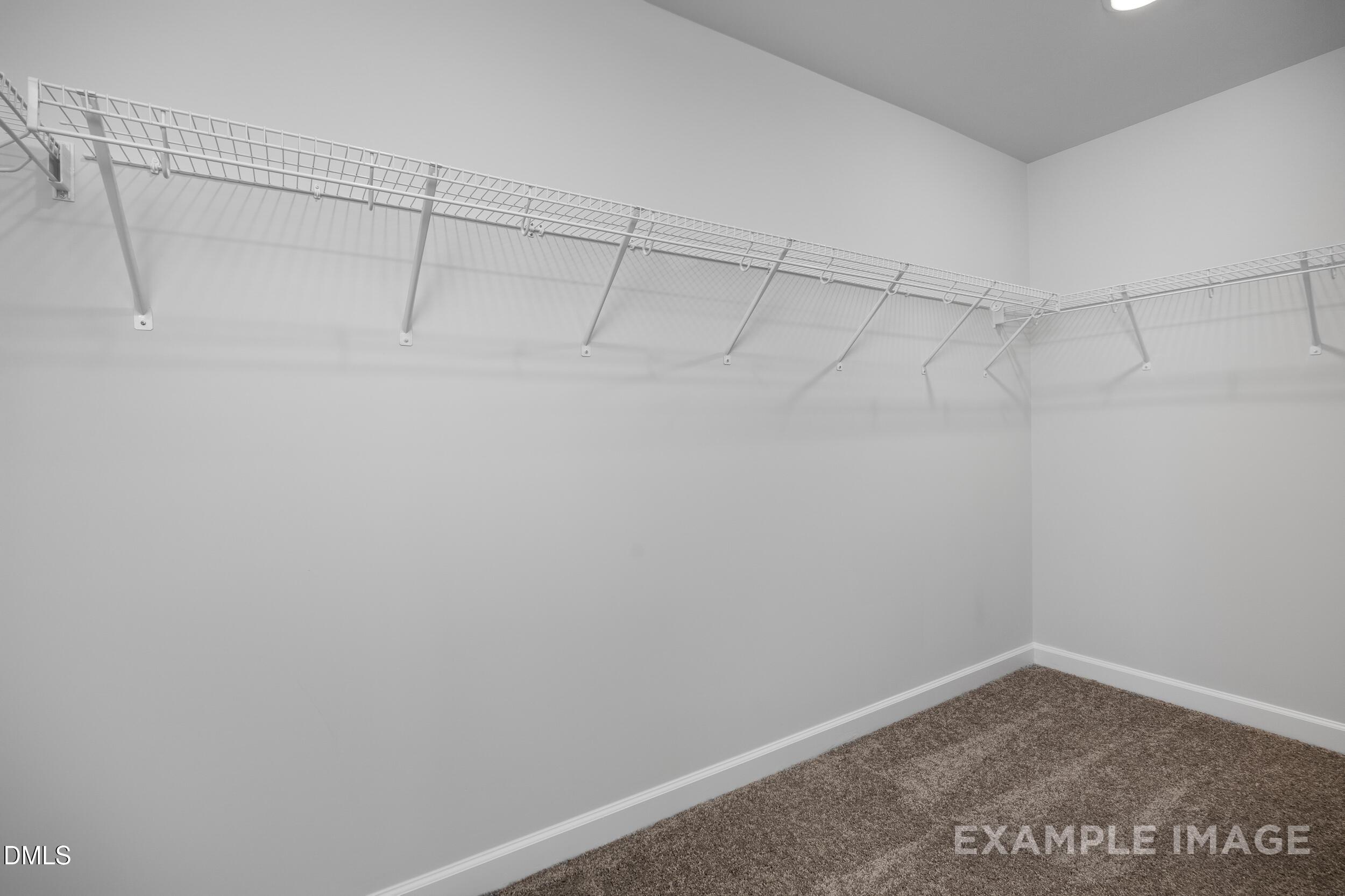Spacious walk-in closet with white wire shelving in The Gavin A floor plan at Gregory Village in Lillington, NC.