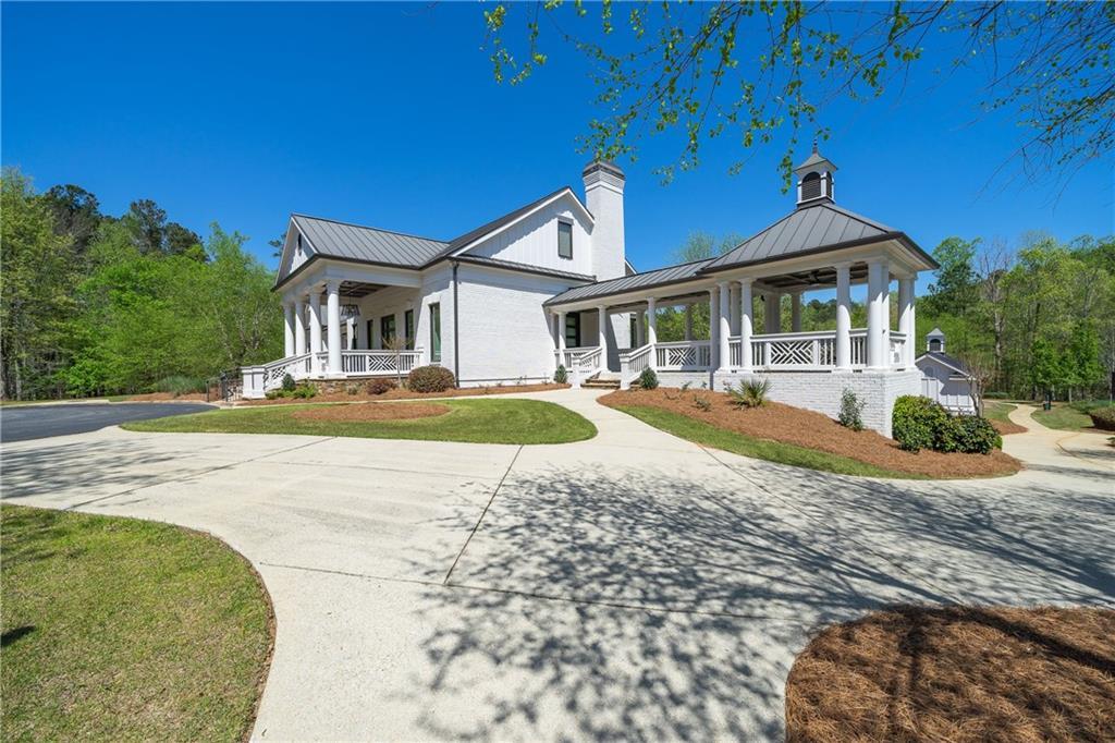 White Craftsman-style 3-bedroom home with metal roof, columned wrap-around porch, 2-car garage, and curved driveway in Riverwood, Dallas, Georgia