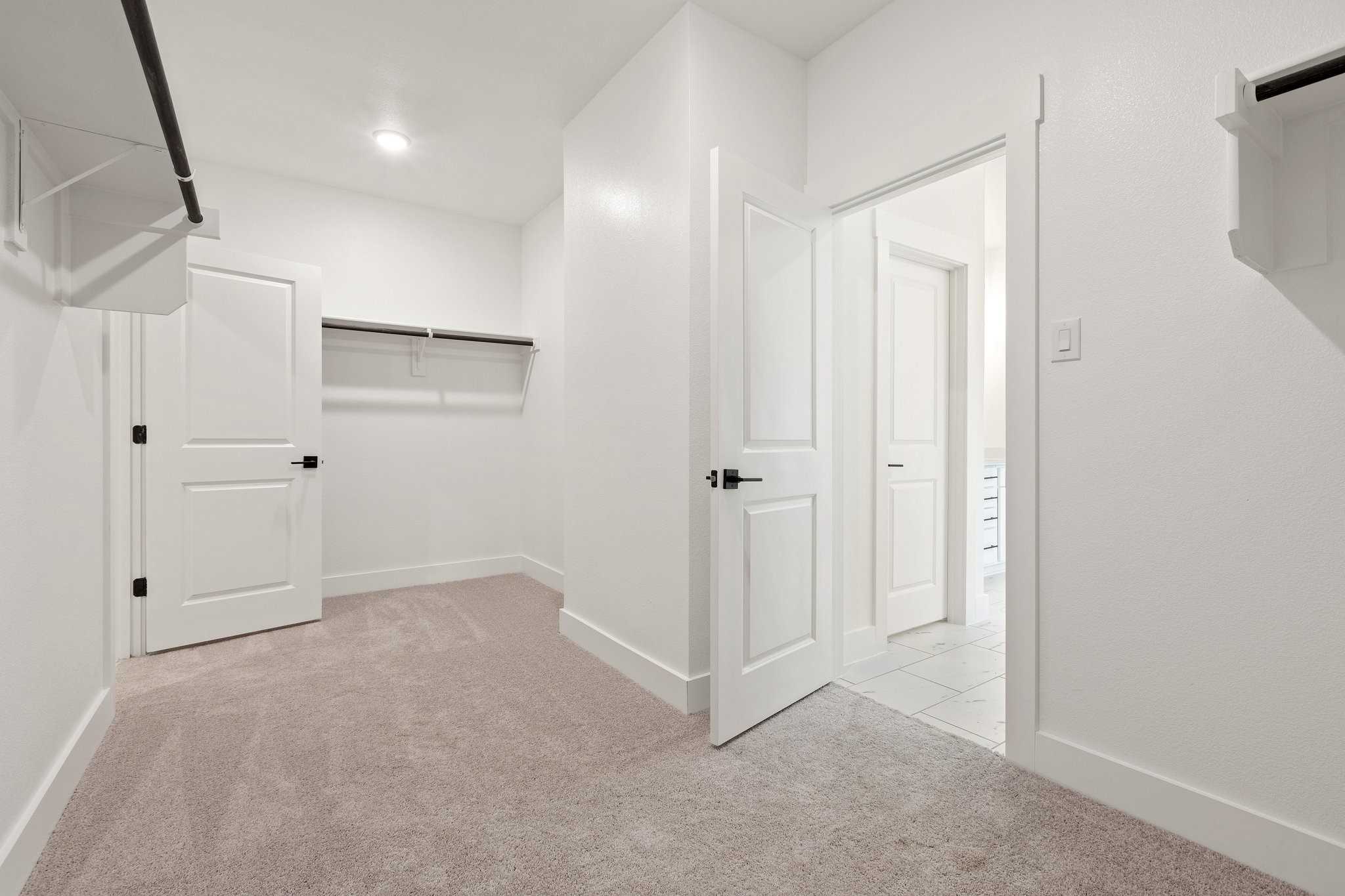 Spacious walk-in closet with built-in shelves, hanging rods, and adjacent bathroom in Davidson Homes The Rockford C, Josephine, Texas