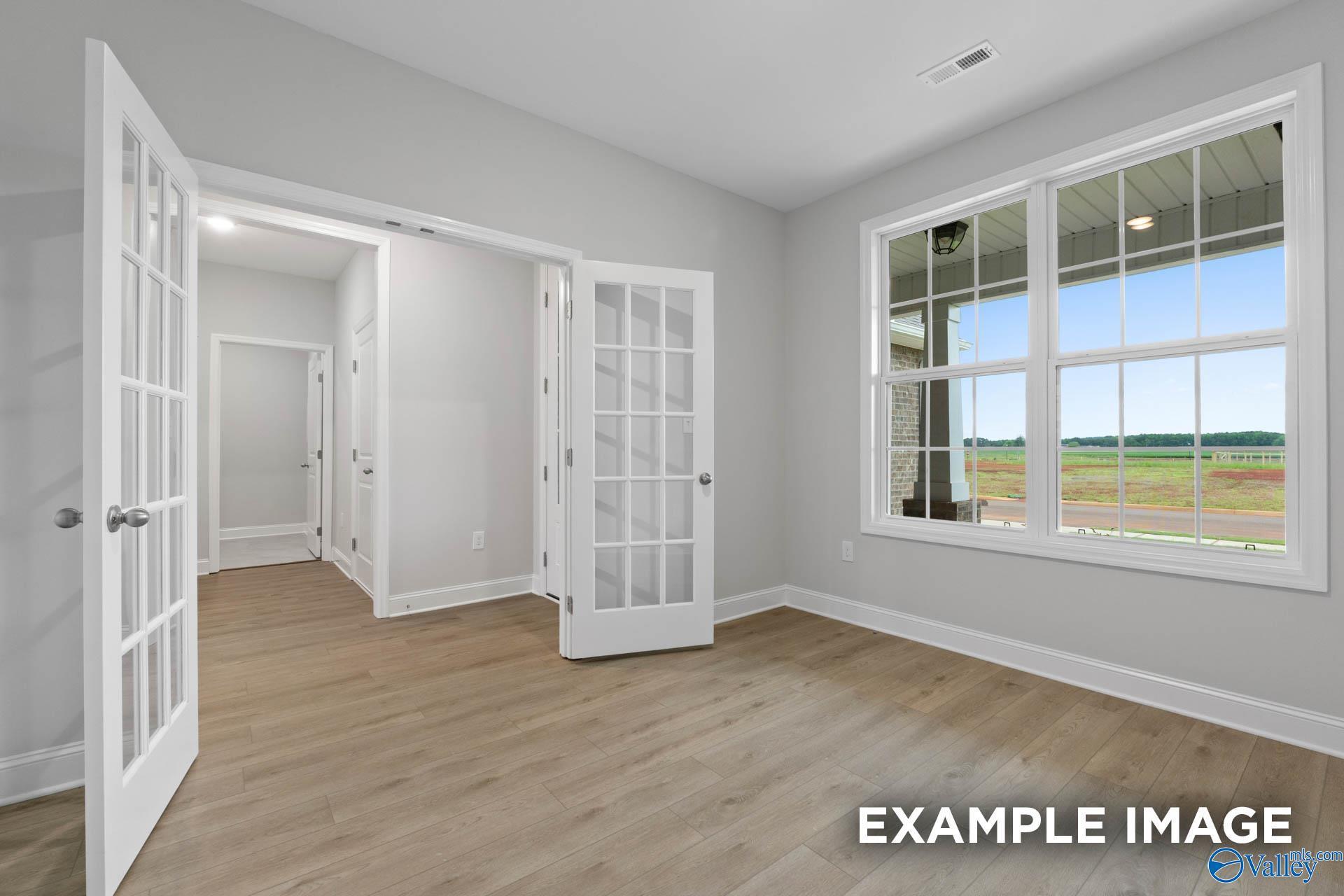 Bright living room with open French doors, hardwood floors, and large windows overlooking backyard in Davidson Homes Rockford B, Toney Alabama