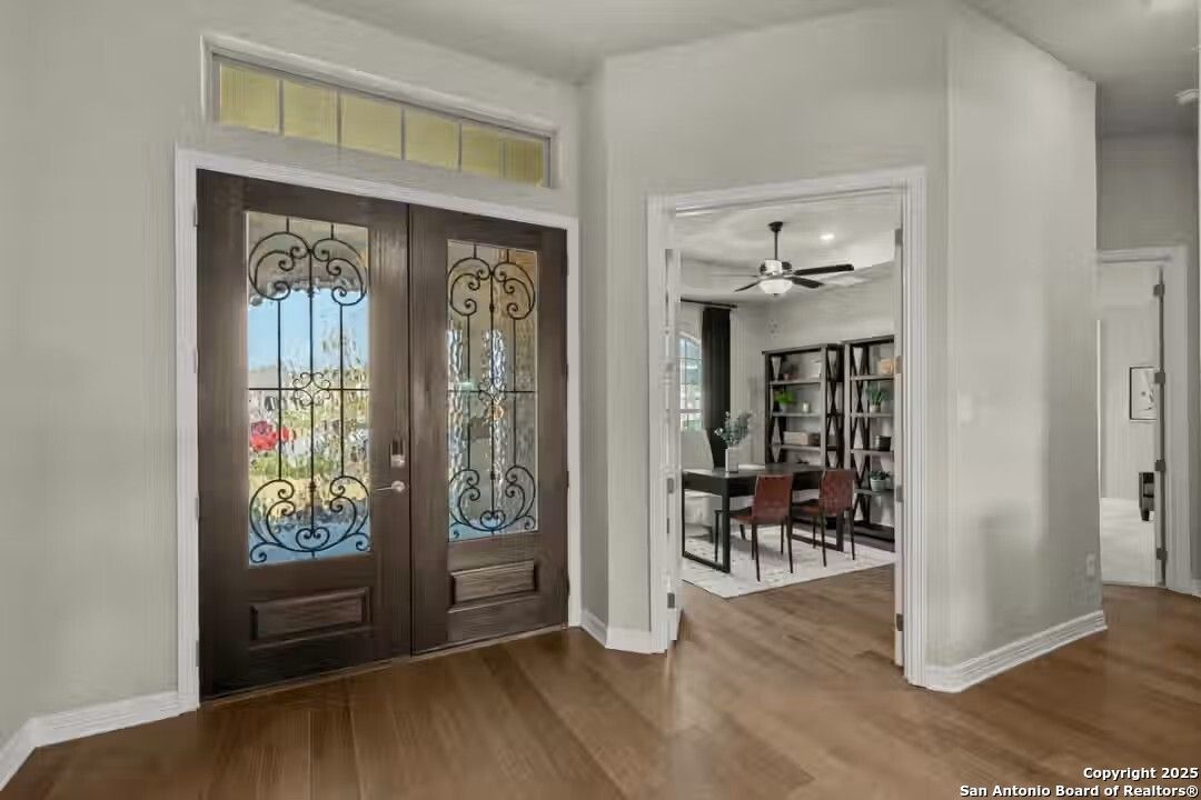 Elegant foyer with ornate wrought iron double doors, hardwood floors, and open dining area in Davidson Homes The Summerlin B, Castroville, Texas