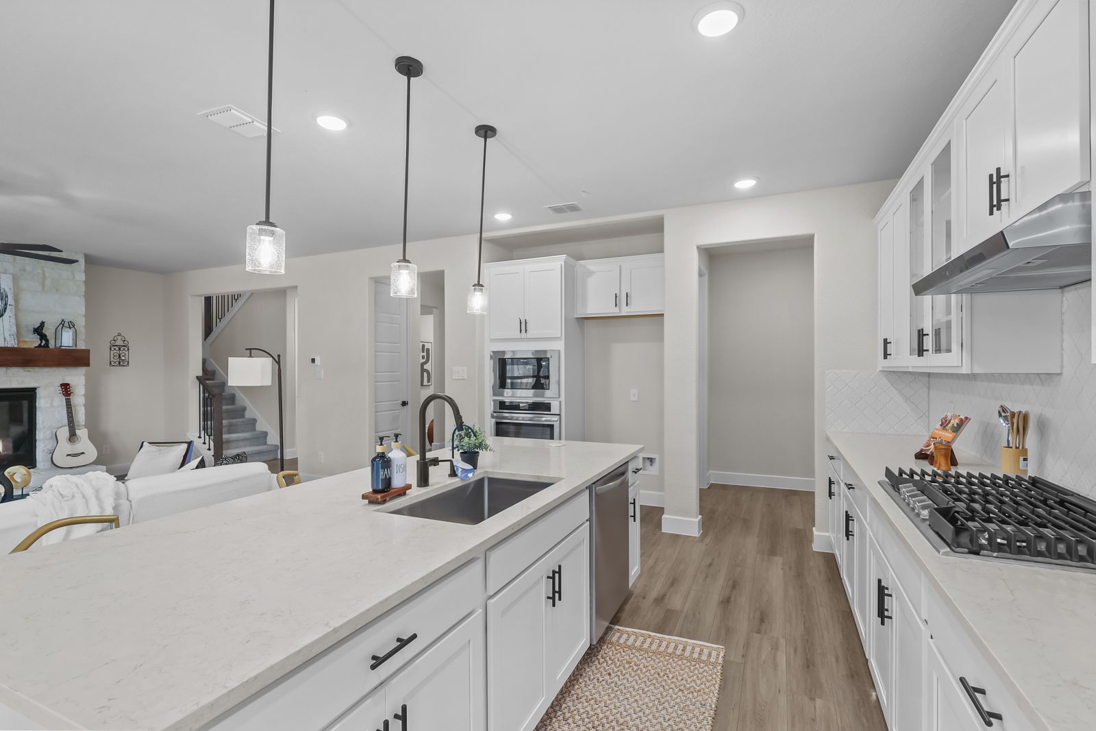 Modern open-concept kitchen in The Belmont J featuring a large island, white cabinetry, and views of the living area.