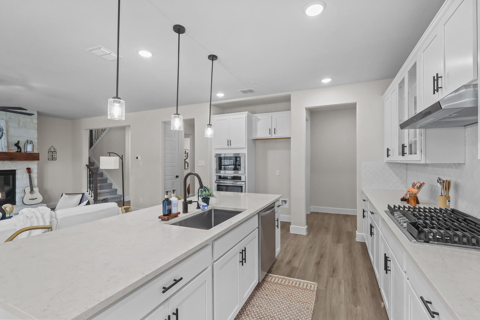 Modern open-concept kitchen in The Belmont J featuring a large island, white cabinetry, and views of the living area.