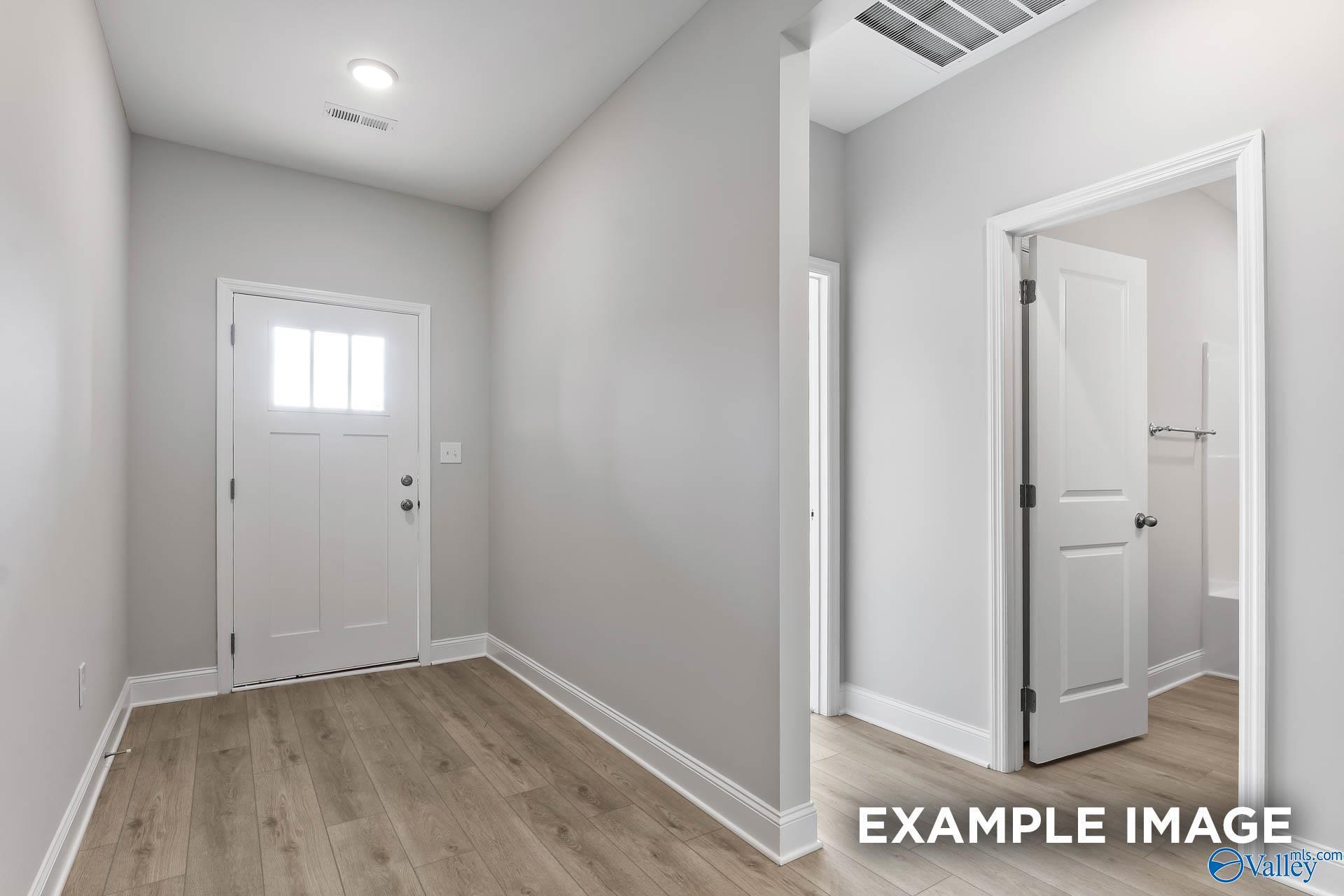 Bright entry hallway with light oak floors, gray walls, white doors in 4-bedroom The Daphne C home, Ivy Hills, Toney, Alabama
