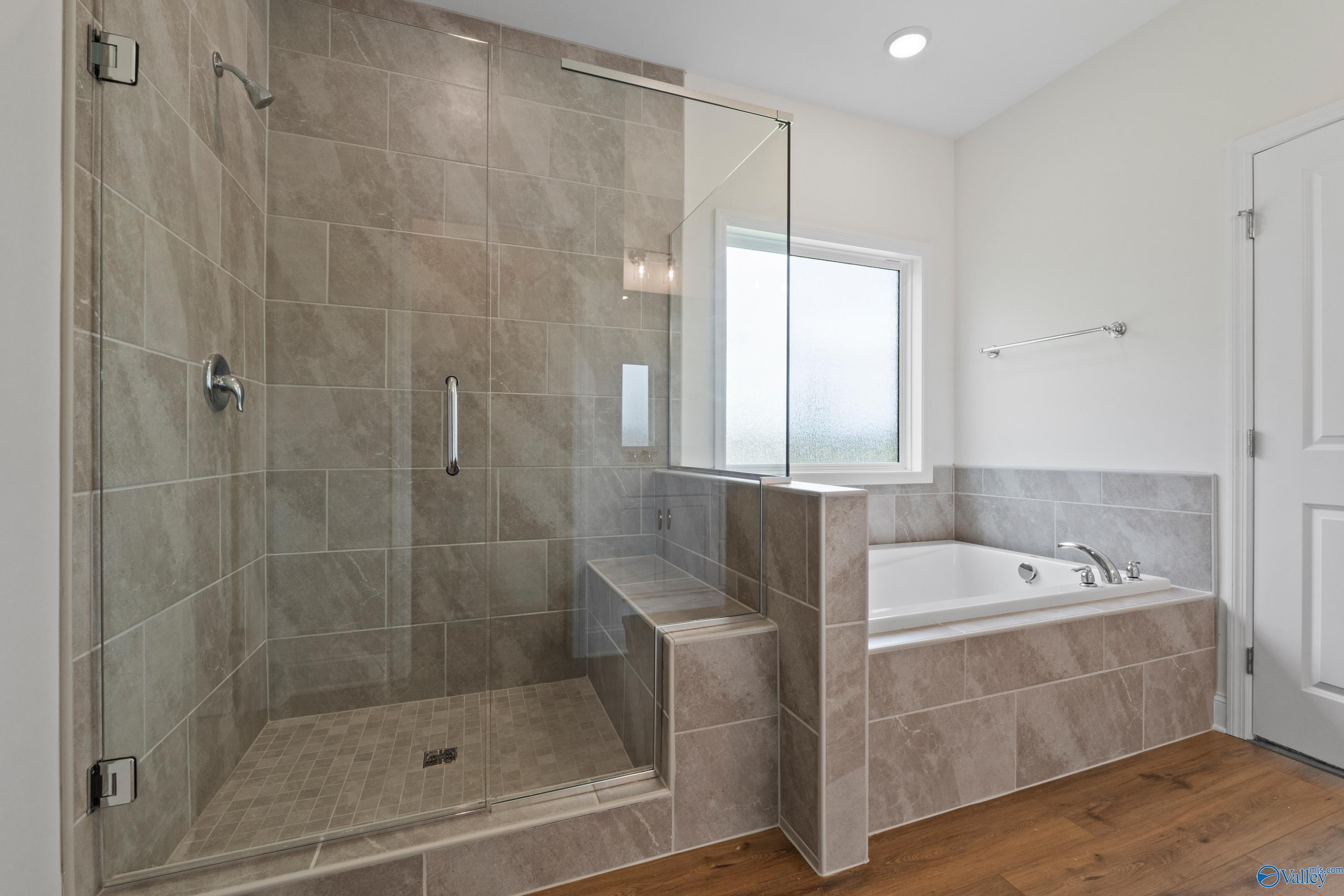 Primary bathroom with tiled walk-in shower and soaking tub in The Everett B floor plan at The Meadows, Athens, Alabama.