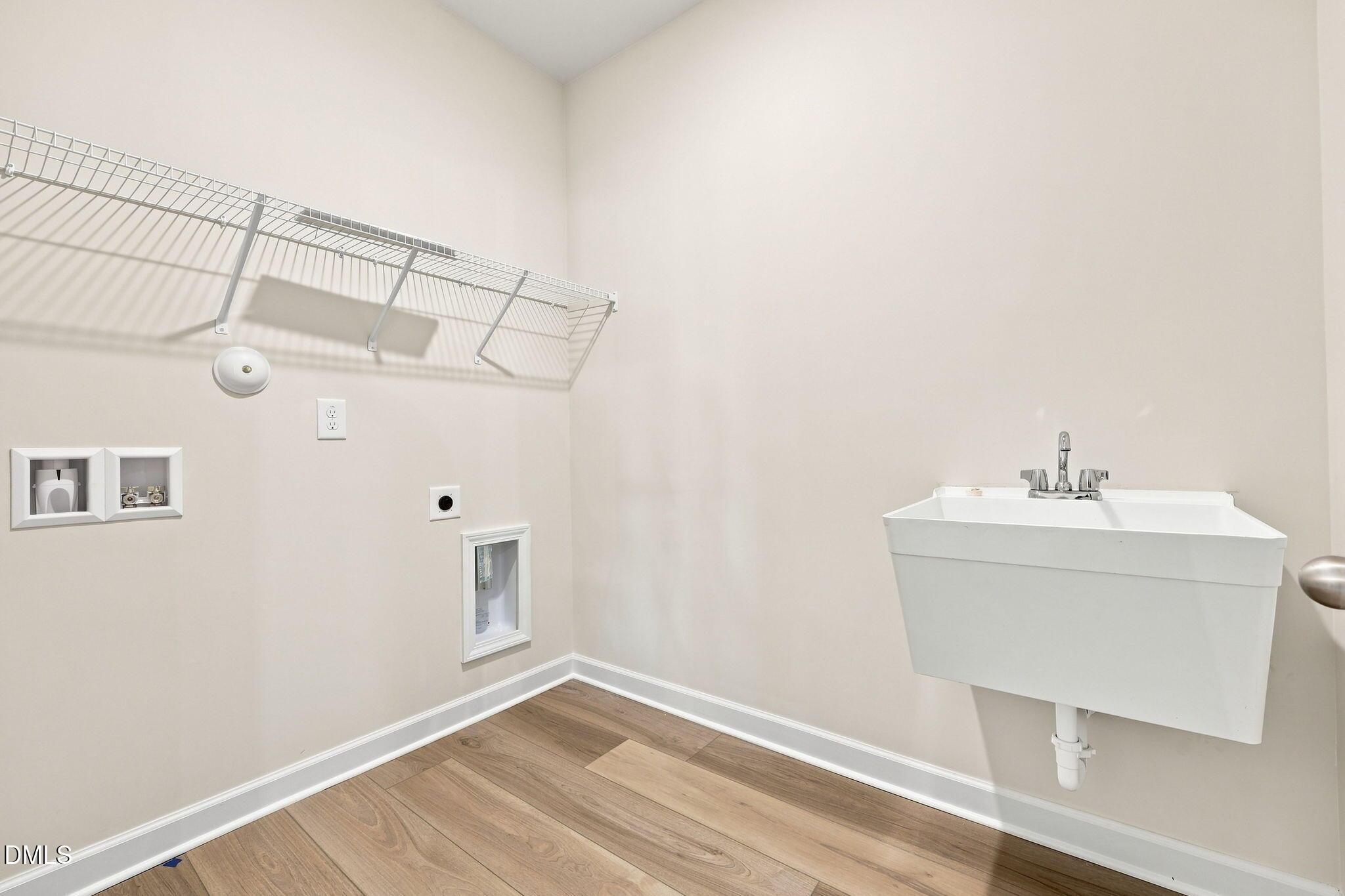 Laundry room with utility sink and shelving in The Magnolia B floor plan at Retreat at North Main in Lillington, NC.