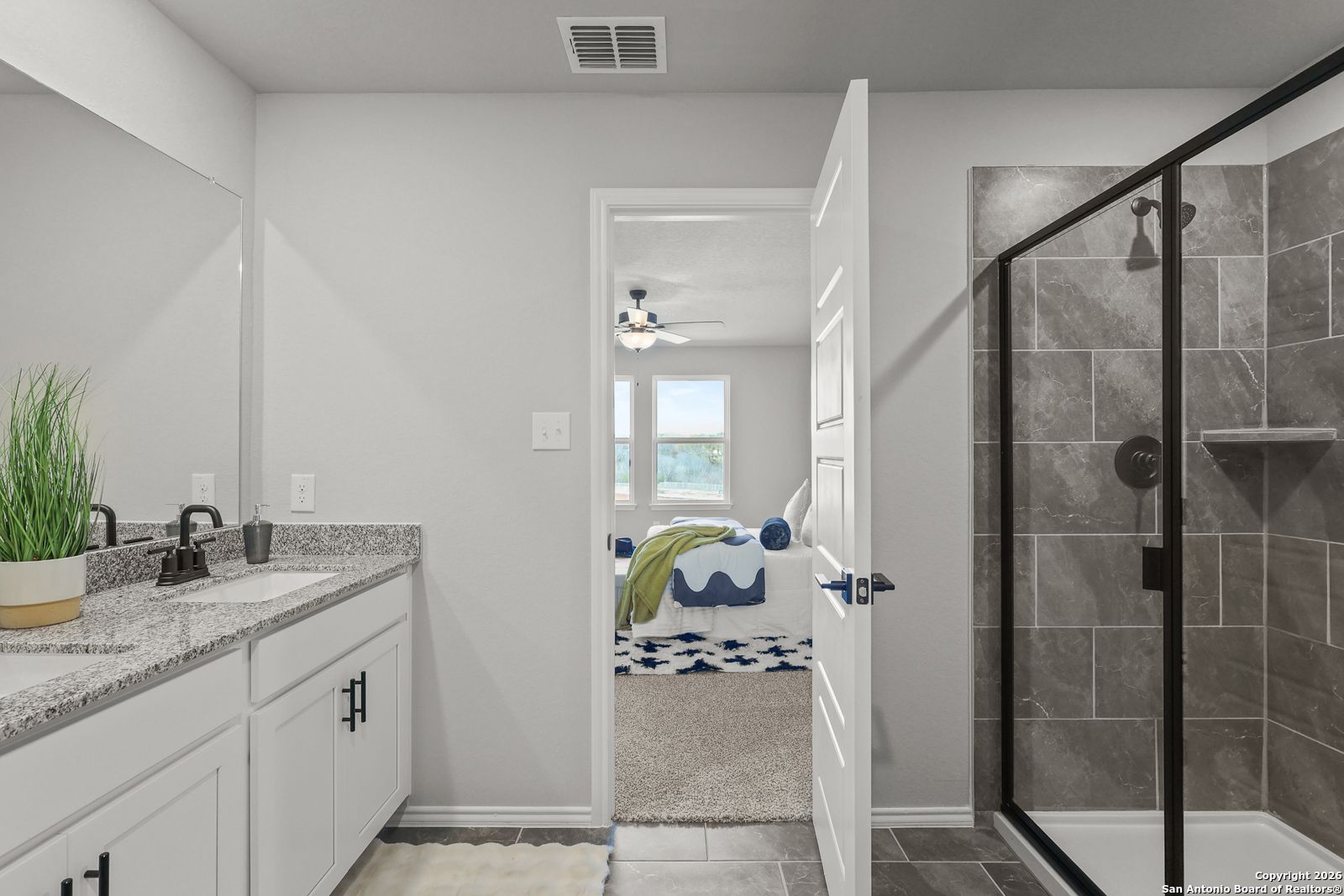 Modern master bathroom with double vanity, glass shower, and open doorway to bedroom in Davidson Homes The Murray K, San Antonio