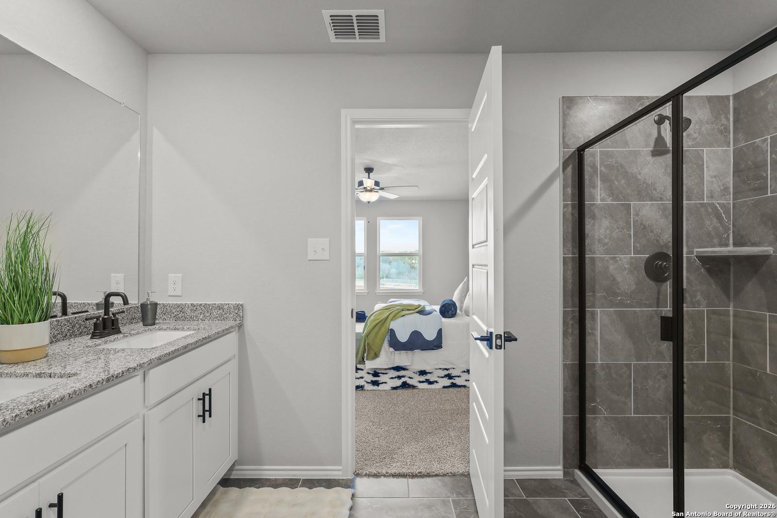 Modern master bathroom with double vanity, glass shower, and open doorway to bedroom in Davidson Homes The Murray K, San Antonio