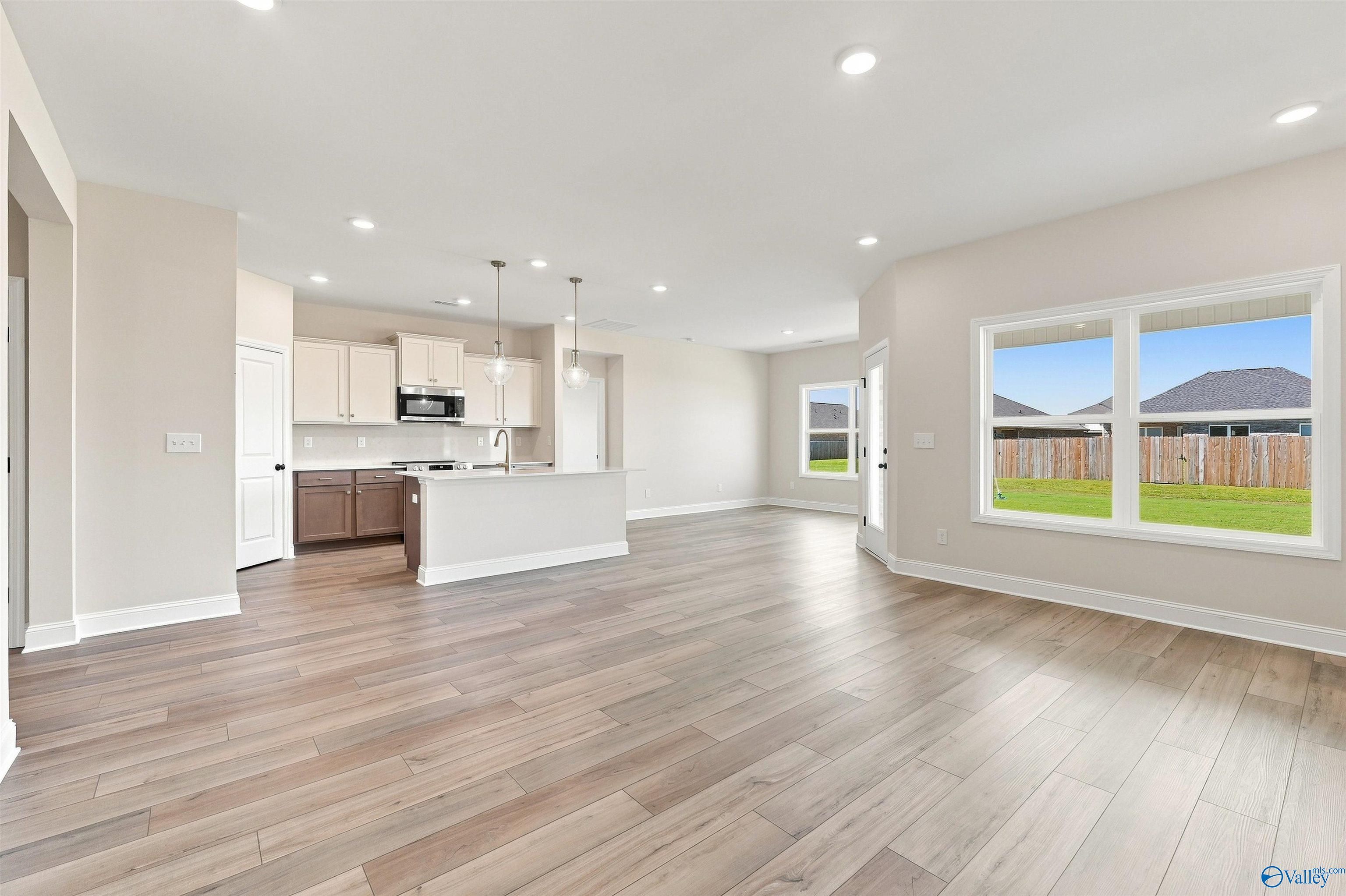Open-concept kitchen and living room with wood-look flooring in Davidson Homes Everett B plan, Ivy Hills, Toney, Alabama