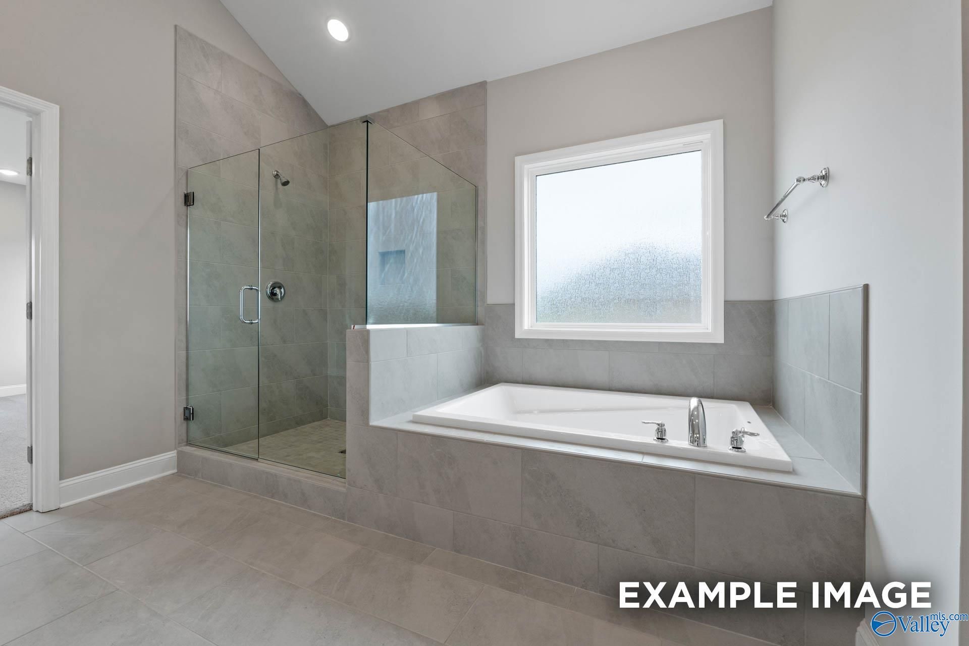 Modern master bathroom featuring glass shower and freestanding tub in Davidson Homes The Finleigh, Harvest, Alabama