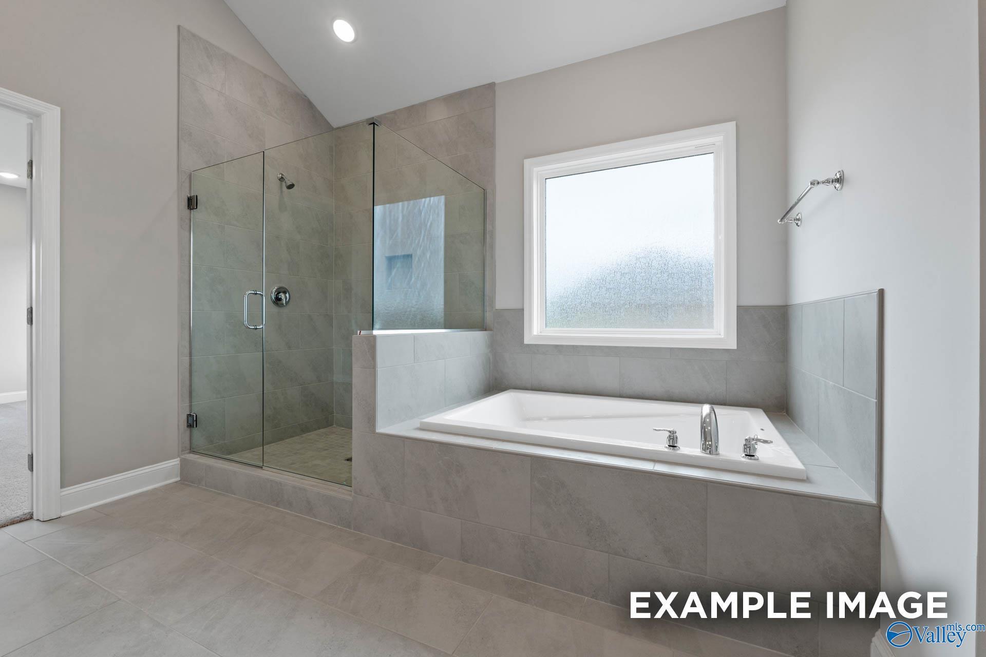Modern master bathroom featuring glass shower and freestanding tub in Davidson Homes The Finleigh, Harvest, Alabama