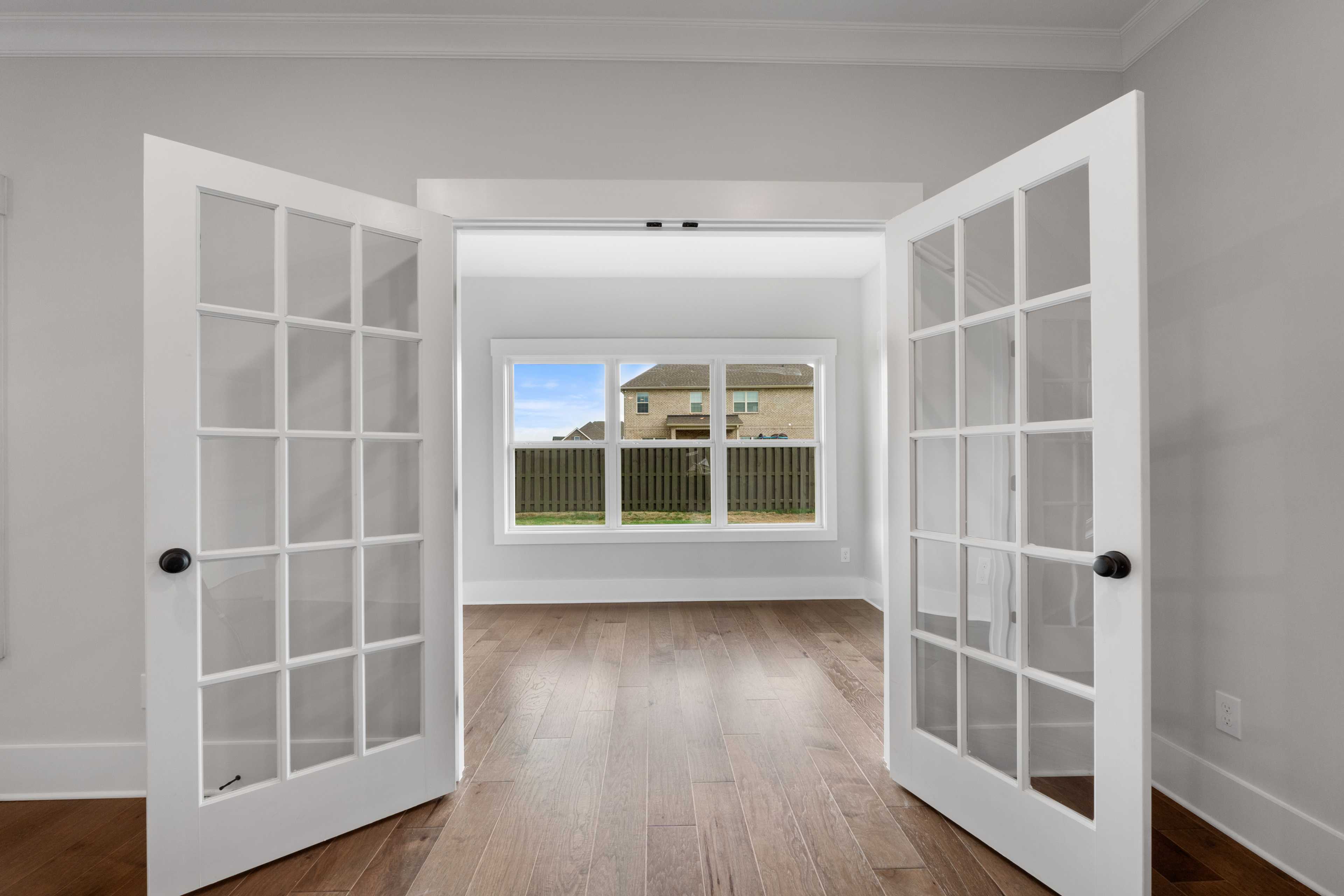 Open French doors to lush backyard view in villa at The Villas at Barnett's Crossing, Madison Alabama, featuring hardwood floors