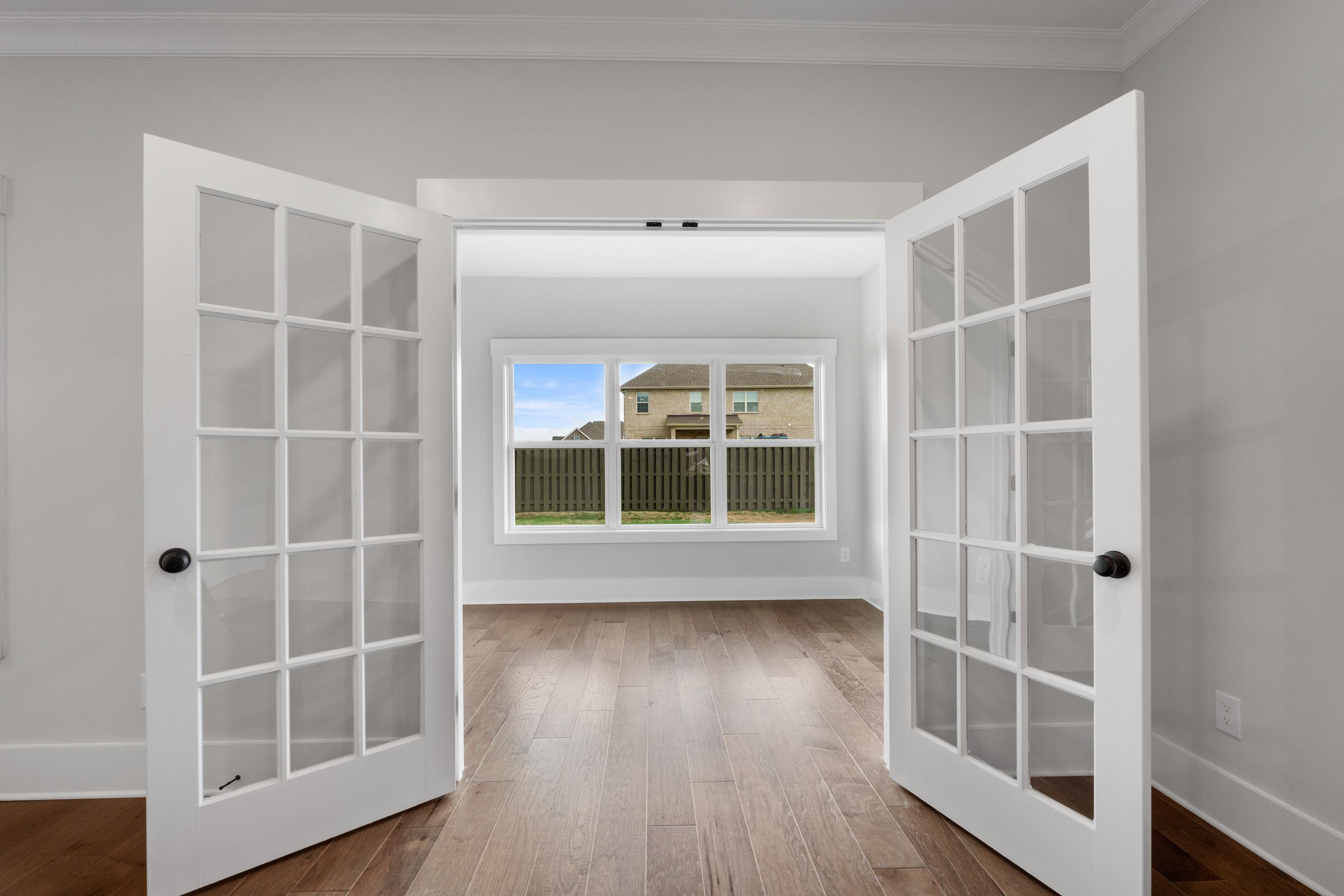 Open French doors to lush backyard view in villa at The Villas at Barnett's Crossing, Madison Alabama, featuring hardwood floors