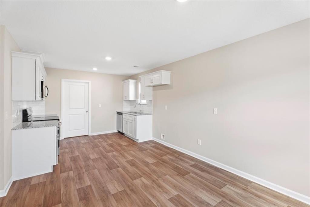Modern white kitchen with cabinets, sink, range, and hardwood floors in Davidson Homes The Washington, Phenix City, Alabama