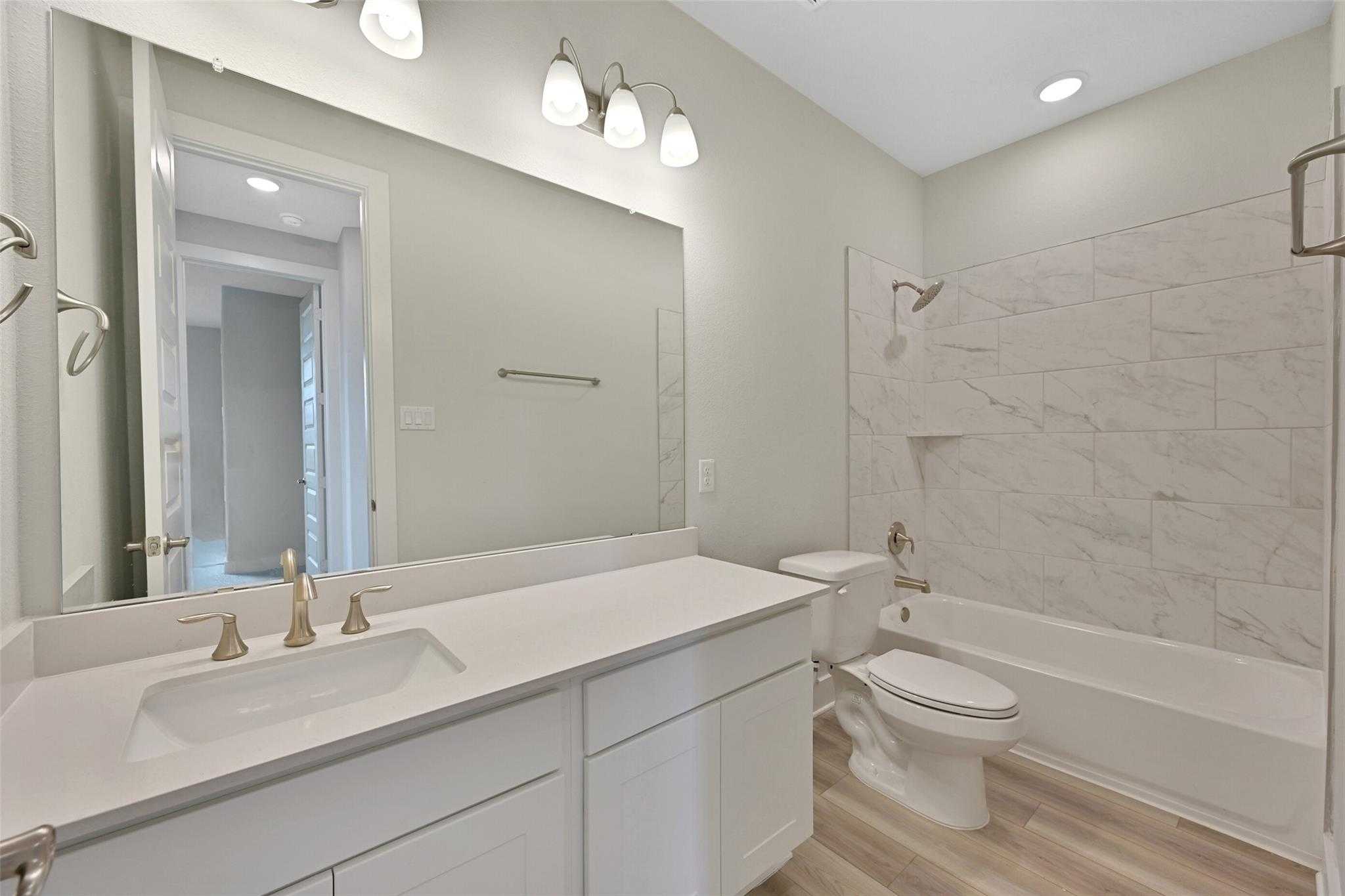 Modern bathroom with double white vanity, quartz countertop, subway tile shower, soaking tub in Davidson Homes The Edward A, Lago Mar, Texas City