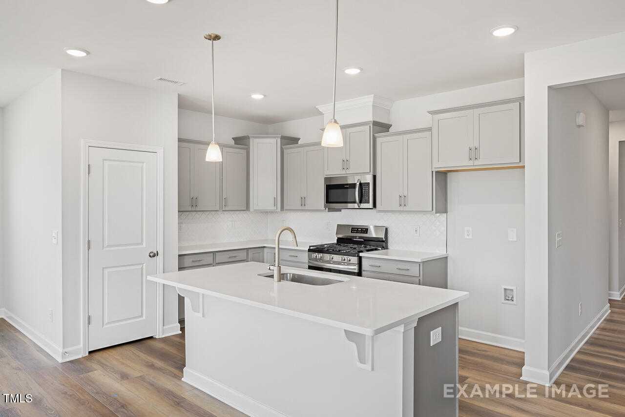 Modern white kitchen with shaker cabinets, quartz island, stainless appliances in The Daphne C 3-bed home, Lillington, NC