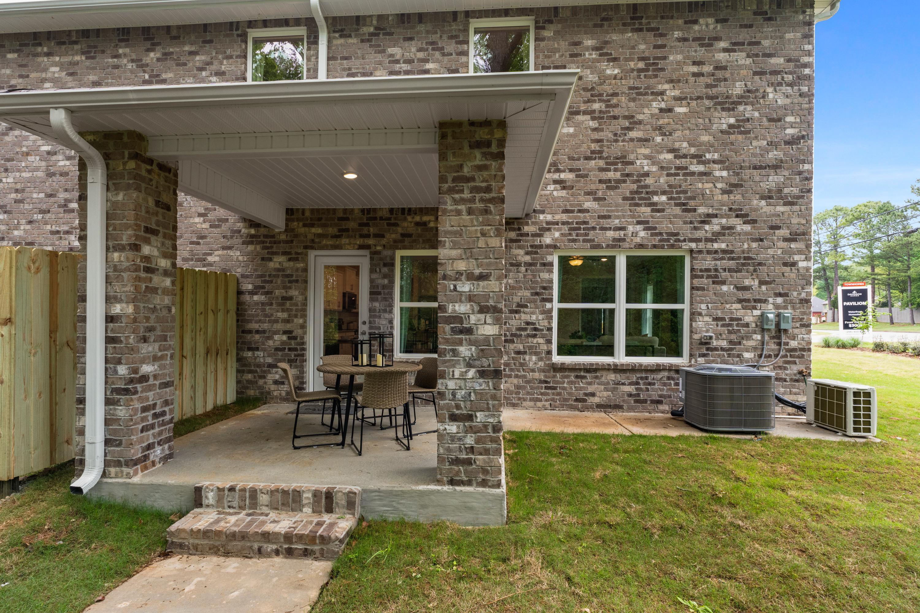 Brick home exterior with covered patio, outdoor seating, and lush yard at Pavilion in Huntsville Alabama