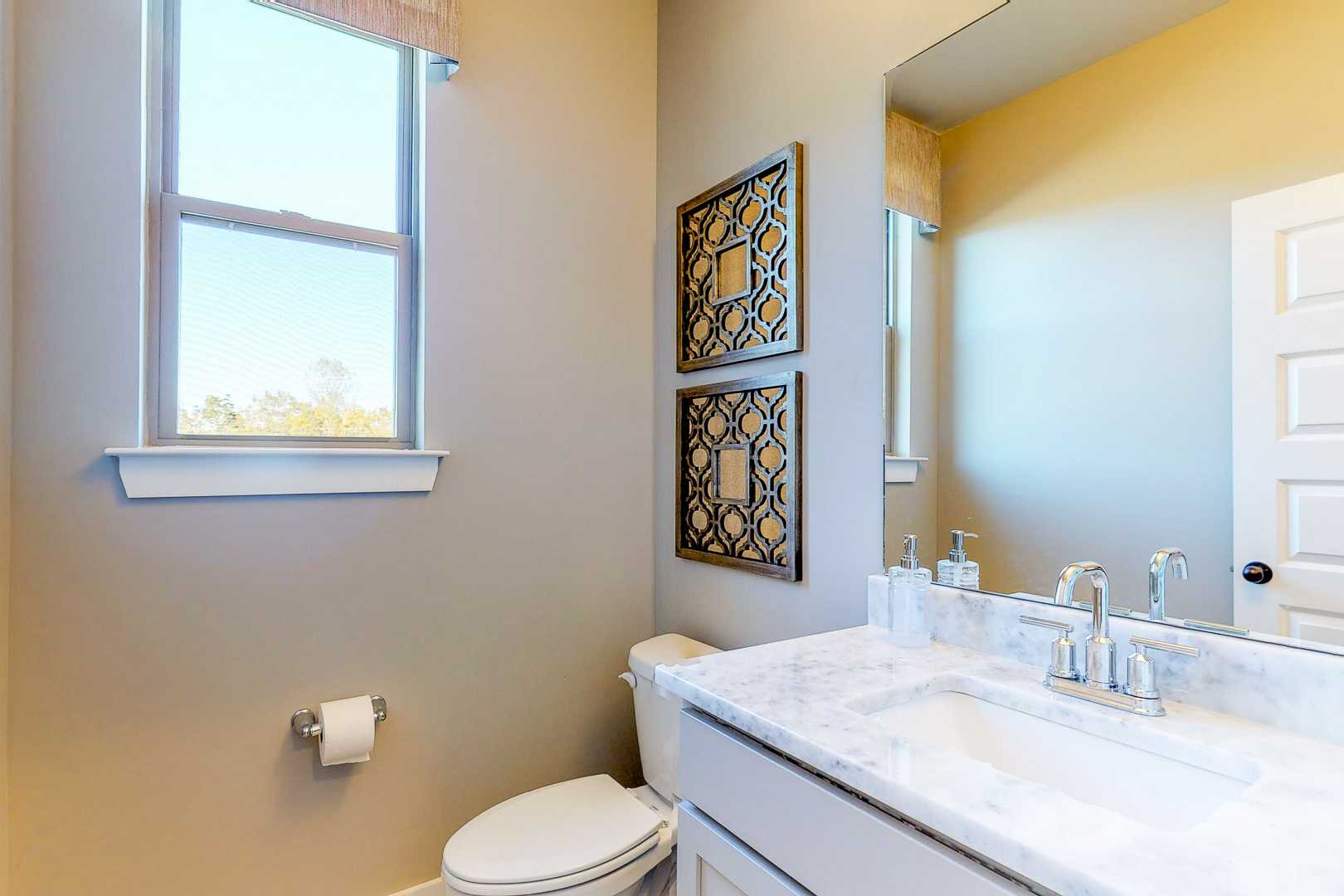 Elegant powder room at Liberty Creek in Gallatin TN with marble vanity, beige walls, large mirror and window