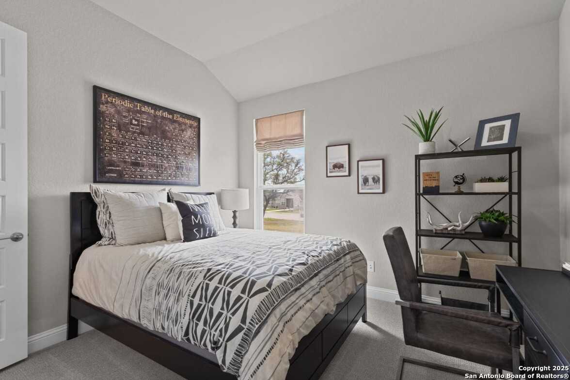 Cozy bedroom with gray walls, queen bed in white-gray bedding, desk, shelves, and window in The Garner B, Ladera, San Antonio