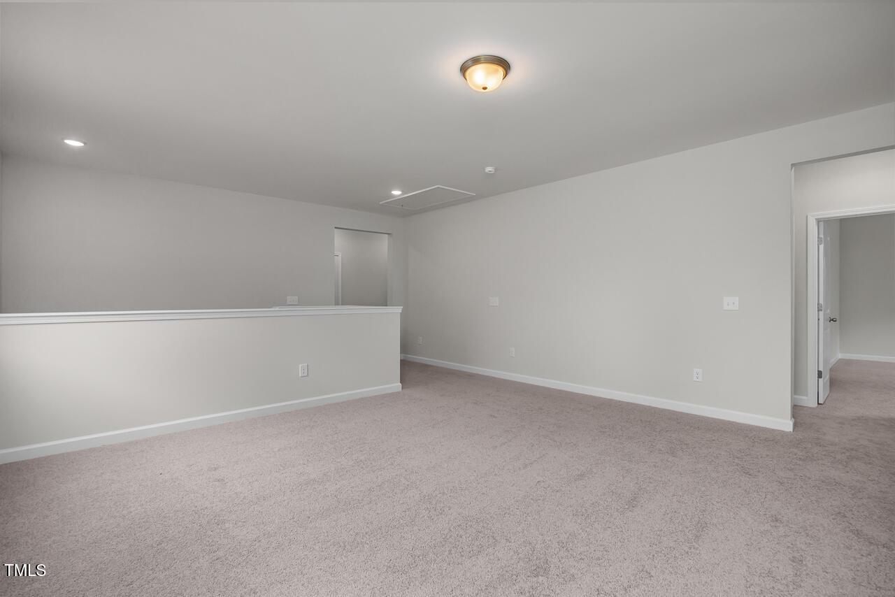 Spacious upstairs loft with beige carpet, gray walls, and balcony railing in The Aspen B 5-bedroom home, Wake Forest