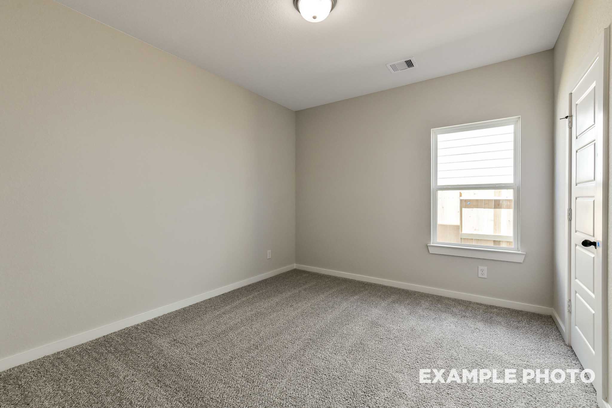 Spacious secondary bedroom in The Daphne G with beige walls, gray carpet, large window, and double doors