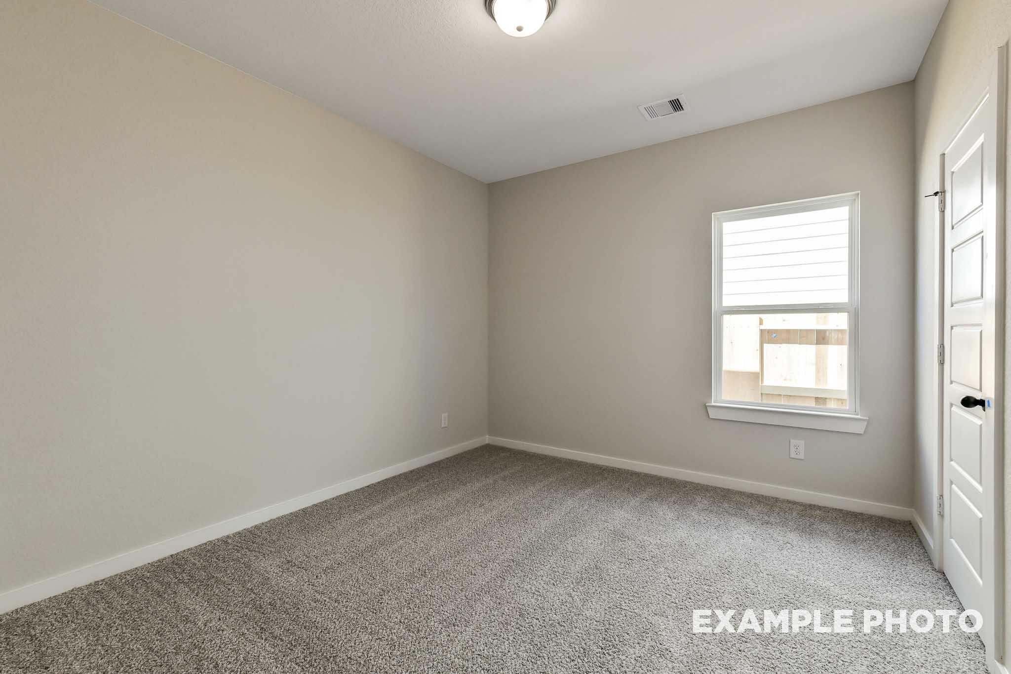 Spacious secondary bedroom in The Daphne G with beige walls, gray carpet, large window, and double doors