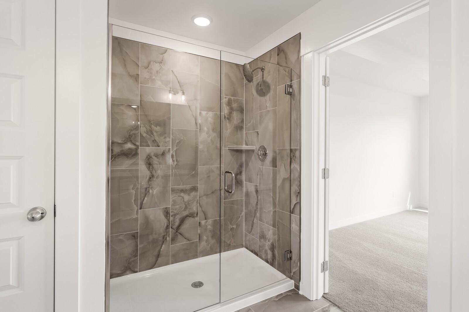 Modern walk-in shower with marble-look tile in The Willow D floor plan at Benders Cove, Mt. Juliet, Tennessee.
