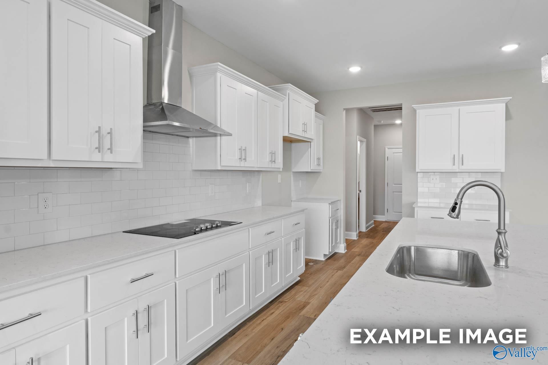 Modern white kitchen with quartz island sink, stainless appliances, subway tile backsplash in The Finleigh by Davidson Homes, Harvest, AL