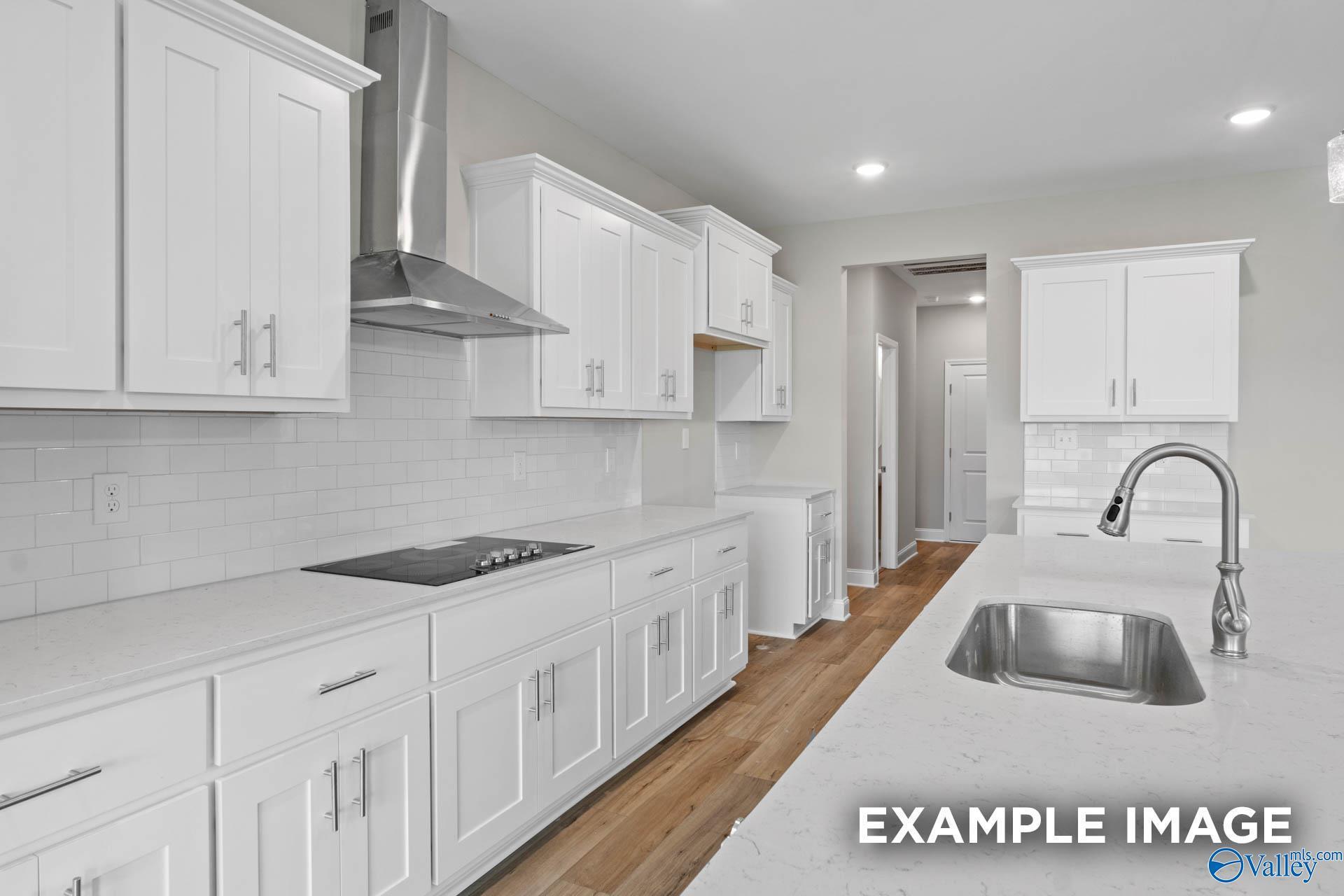 Modern white kitchen with quartz island sink, stainless appliances, subway tile backsplash in The Finleigh by Davidson Homes, Harvest, AL