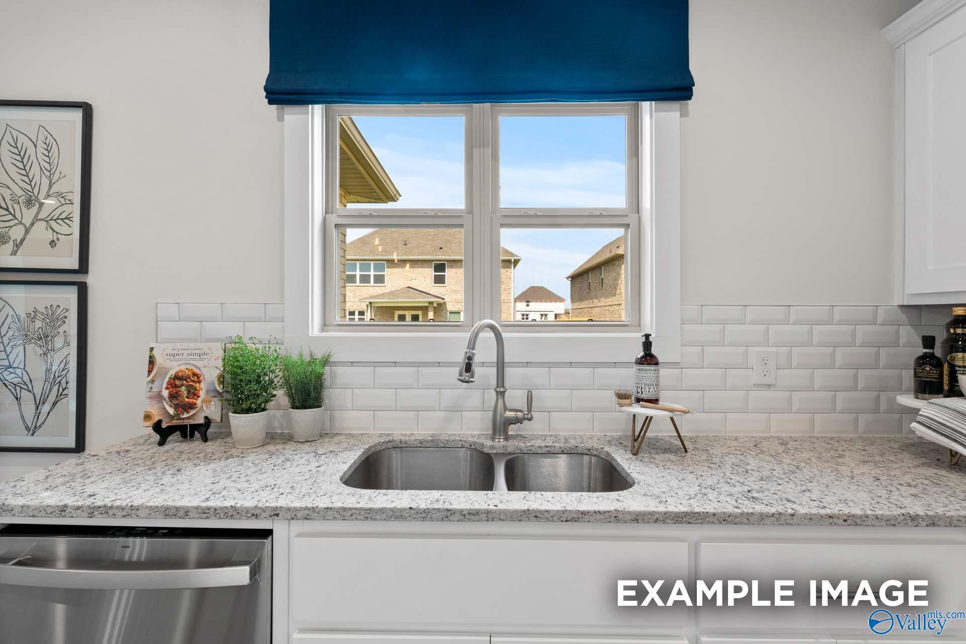 Kitchen sink under window with subway tile backsplash, granite countertops, and white cabinetry in Davidson Homes Chelsea A plan, Toney