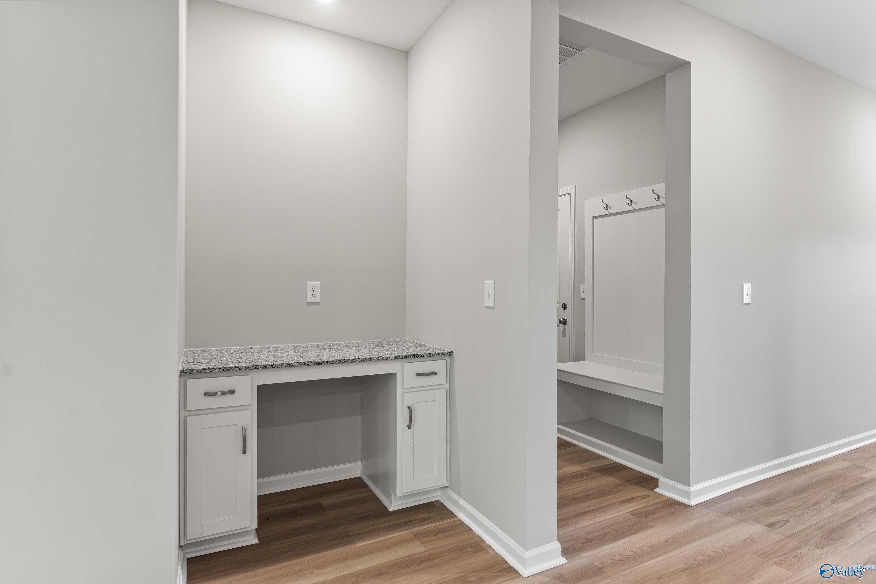 Built-in white desk with granite top and bench with hooks in mudroom, Davidson Homes The Phoenix, Hazel Green AL