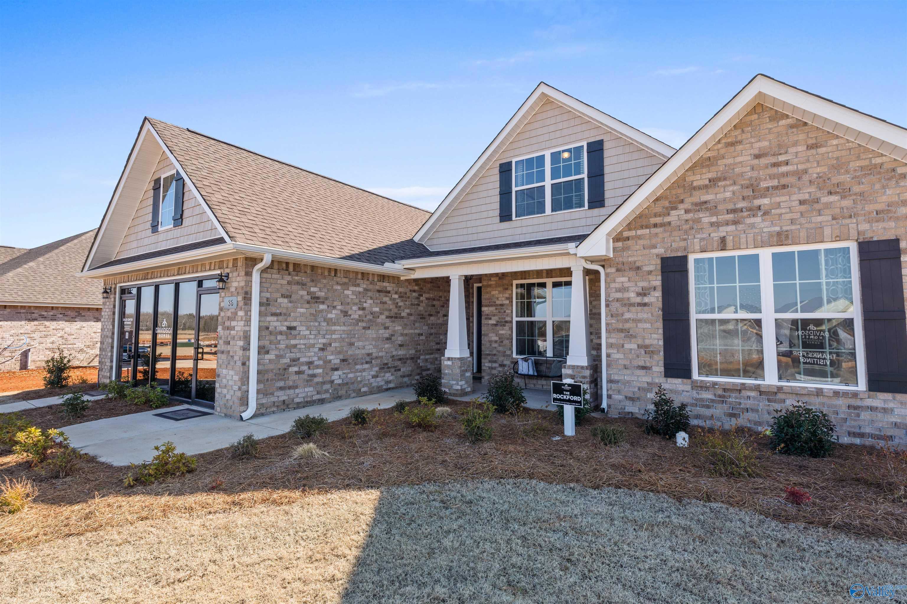 Tan brick 1-story home with gabled roof, covered porch, and large windows in Barnett's Crossing, Madison, Alabama by Davidson Homes