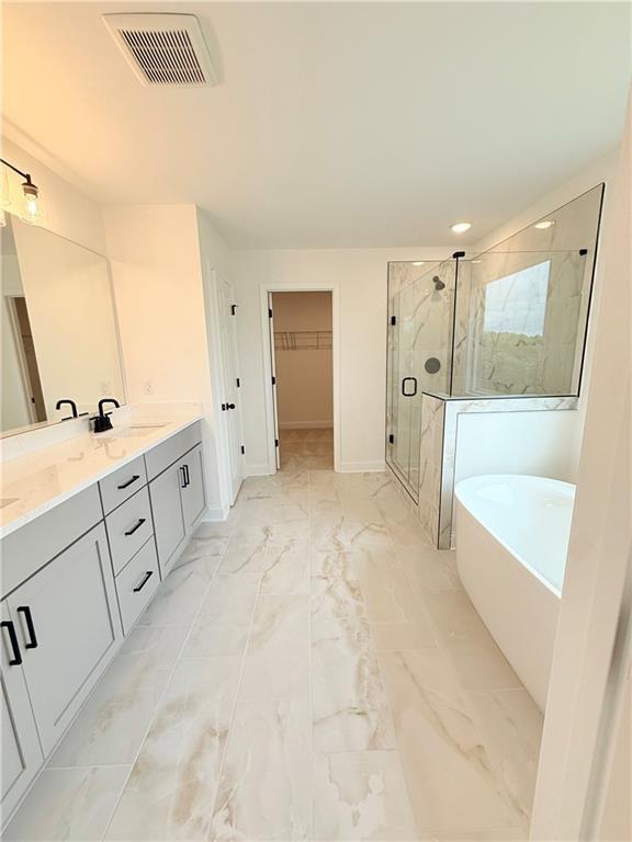 Modern master bathroom with dual vanity, glass-enclosed shower, and soaking tub in The Hickory B at Wehunt Meadows, Hoschton.