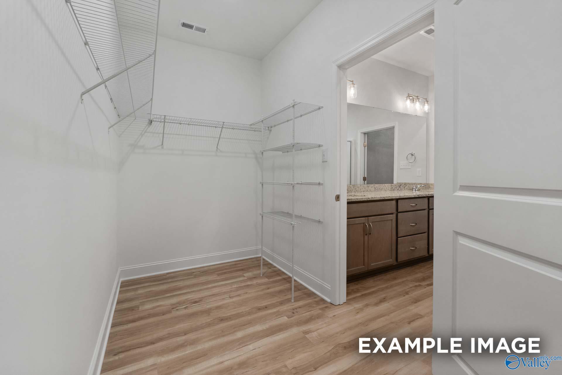 Spacious walk-in closet with wire shelving next to modern bathroom vanity in Davidson Homes The Cumberland B, Decatur, Alabama