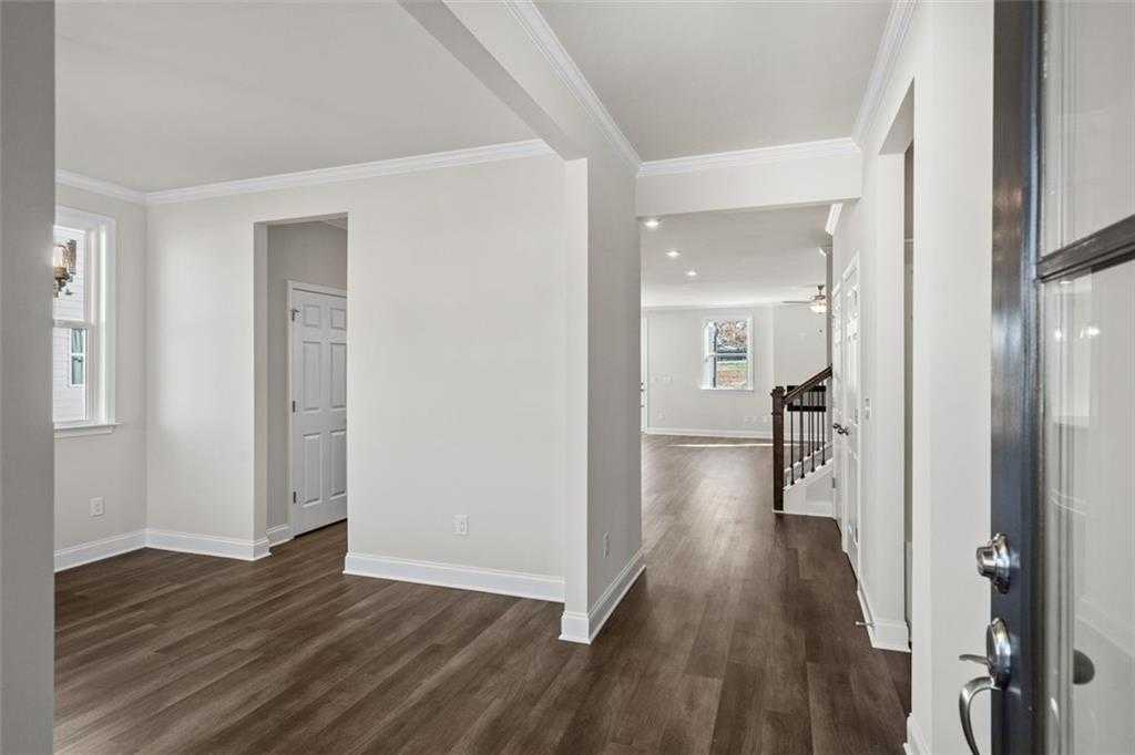 Elegant entry foyer with hardwood floors, grand staircase, and white trim in Davidson Homes The Ash C at Wehunt Meadows, Hoschton, Georgia