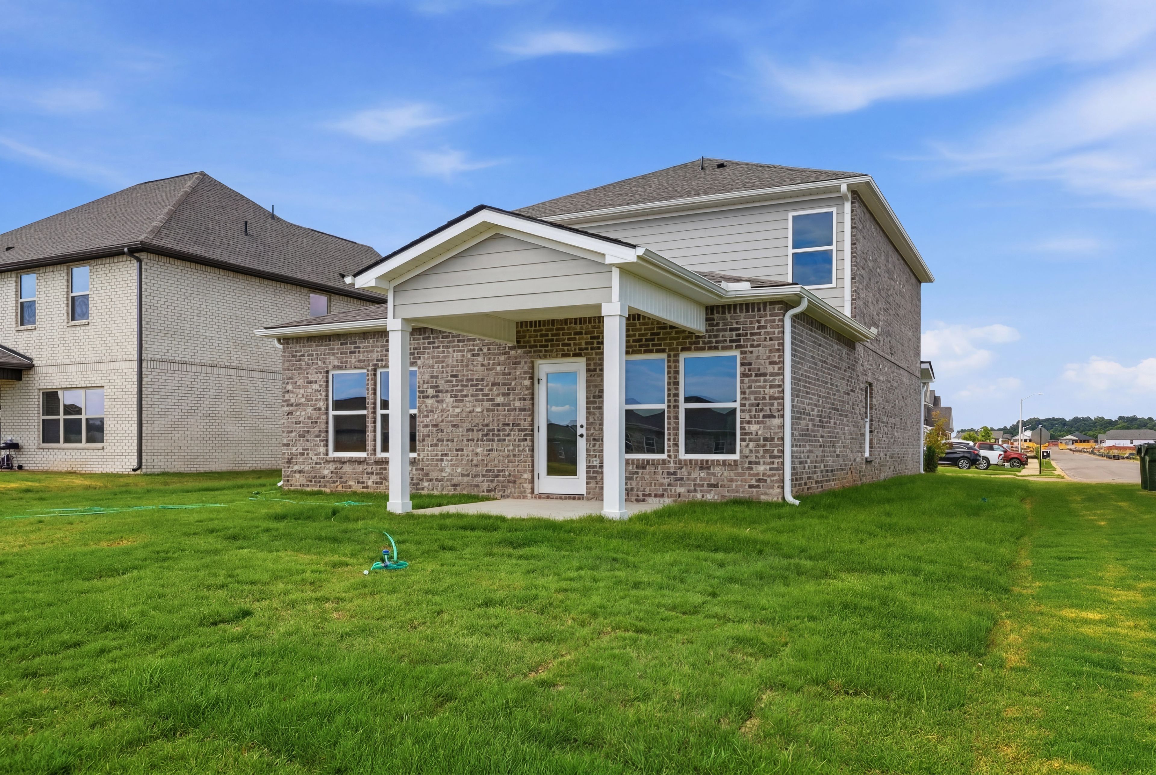 Exterior rear view of The Meadowbrook A in Meridianville featuring brick siding, a covered patio, and large backyard.