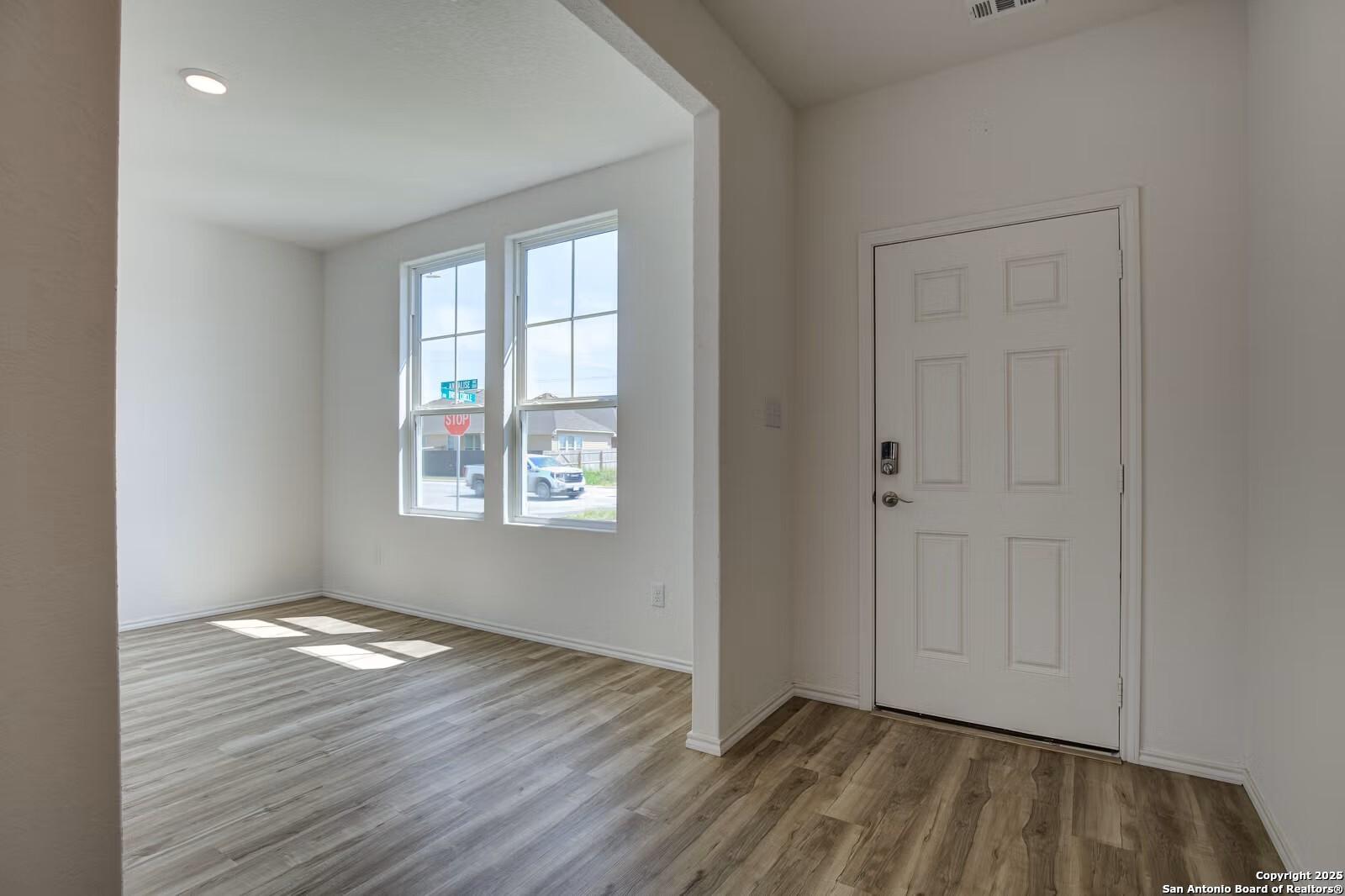Bright entryway with large windows, wood flooring, and white door in Davidson Homes The Douglas B, Seguin Texas
