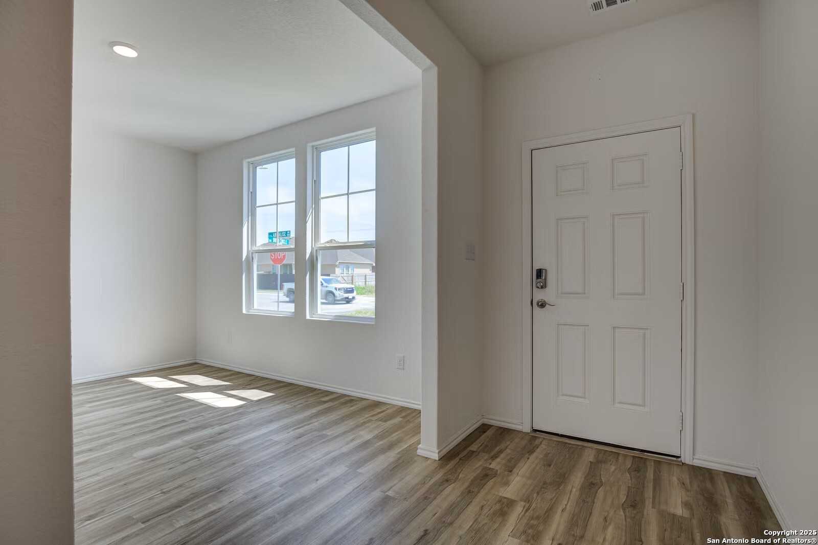 Bright entryway with large windows, wood flooring, and white door in Davidson Homes The Douglas B, Seguin Texas