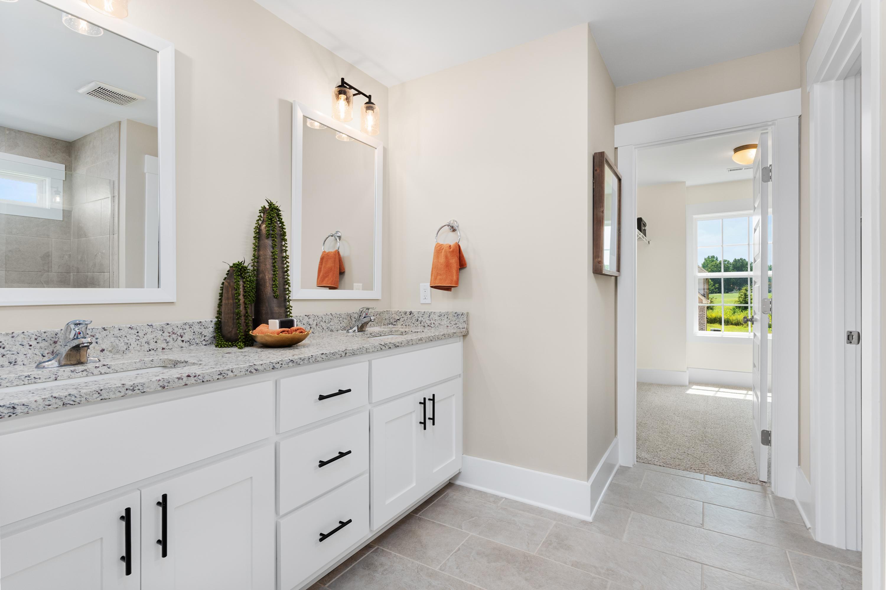 Spacious master bathroom in The Shelby A featuring double vanity with white cabinets, quartz counters, and orange accents