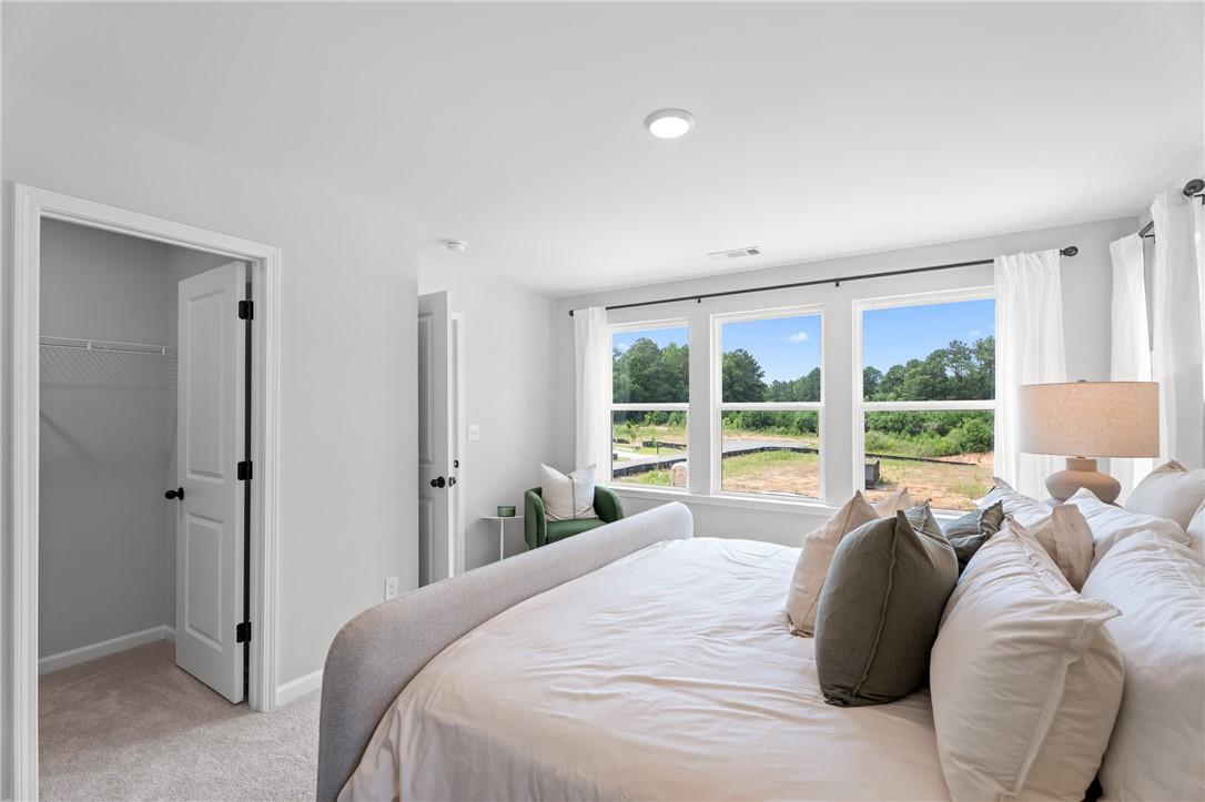 Bright primary bedroom with upholstered bed and large windows in Davidson Homes The Stella B, Anderson Lakes, Opelika, Alabama