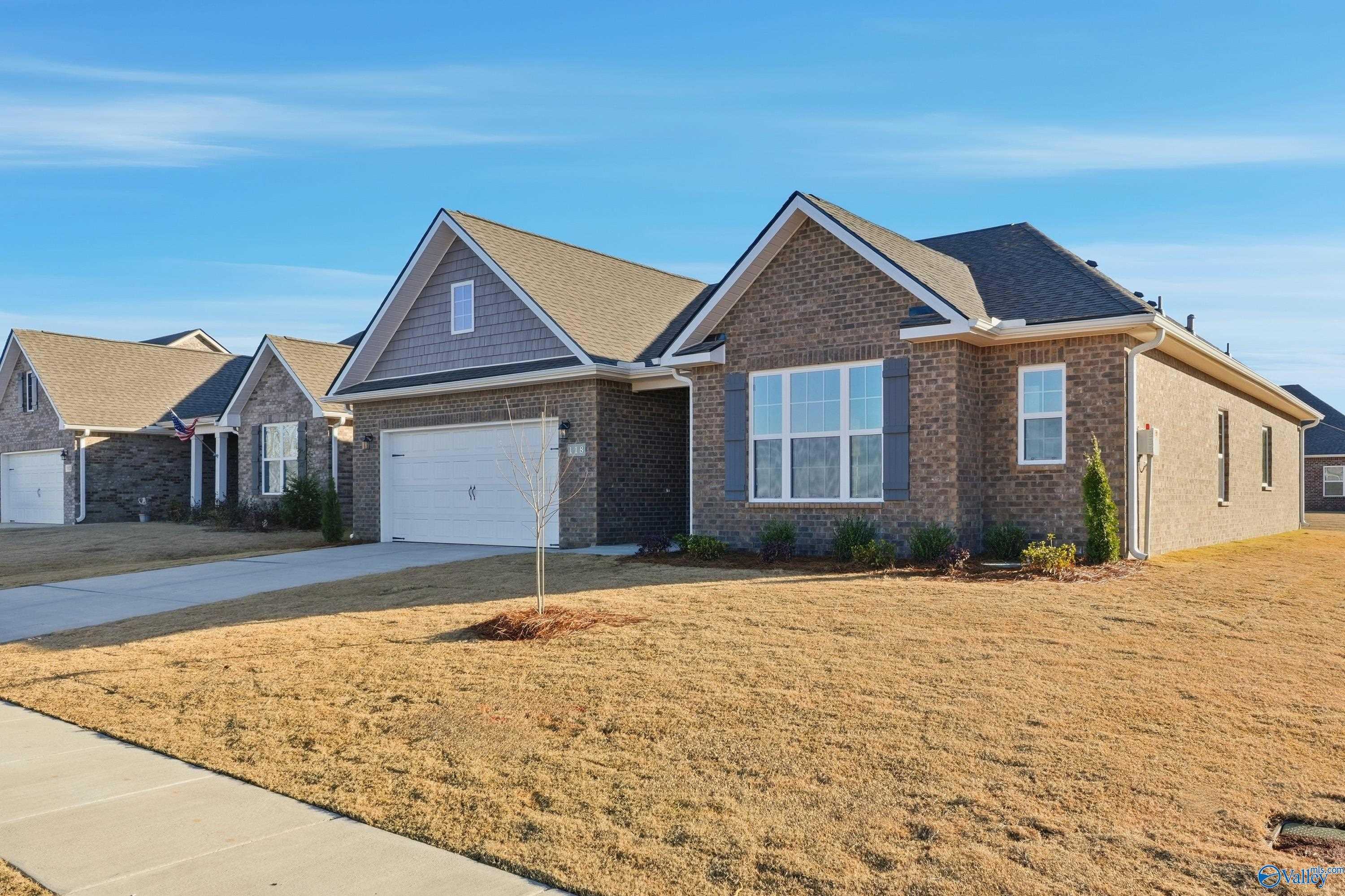 Brick 1-story home with gabled roof, 2-car garage, driveway, and shrubs in Kendall Downs, Toney, Alabama - Davidson Homes Montgomery B