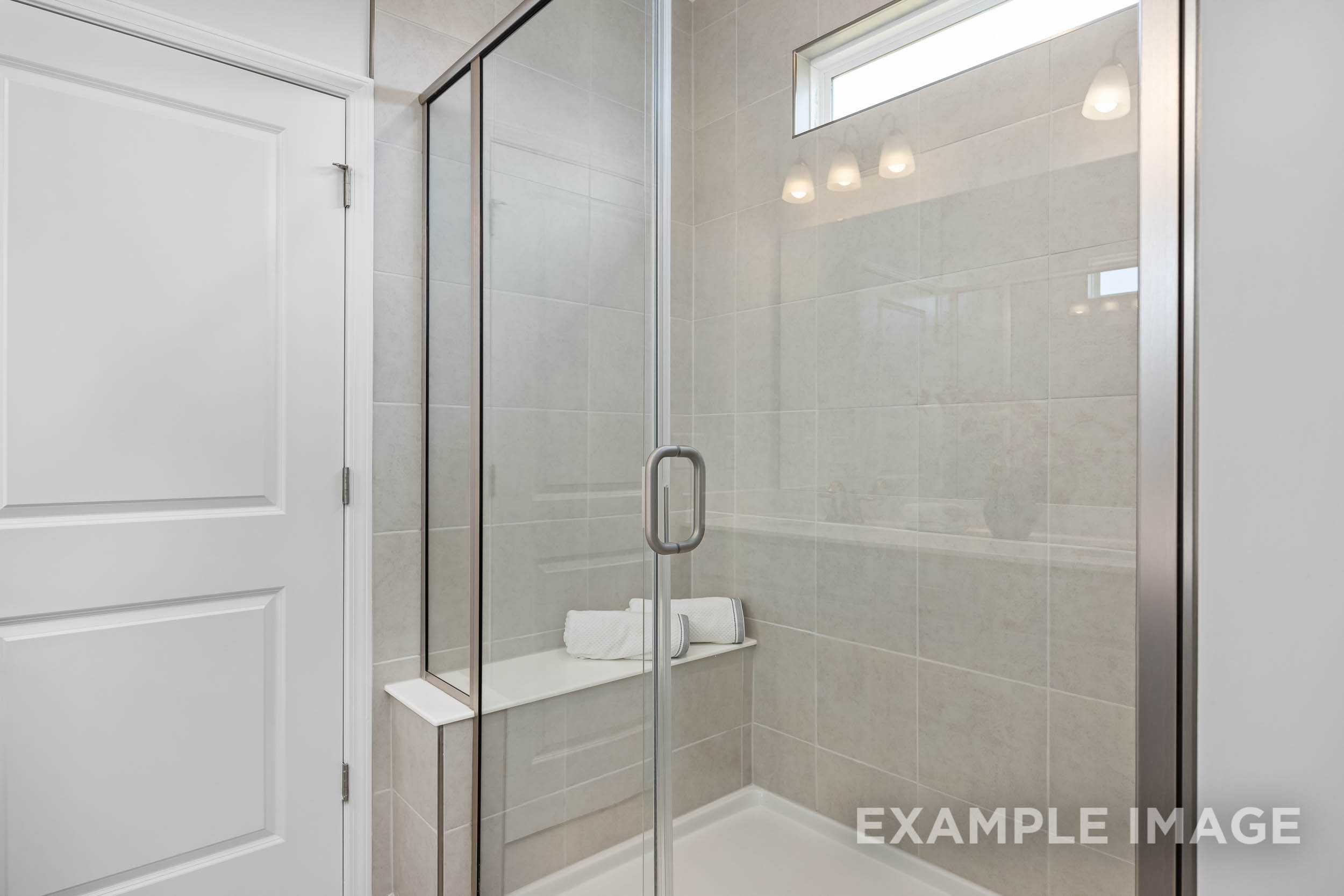 Modern master bathroom in The Daphne C featuring frameless glass shower, subway tile, and built-in bench