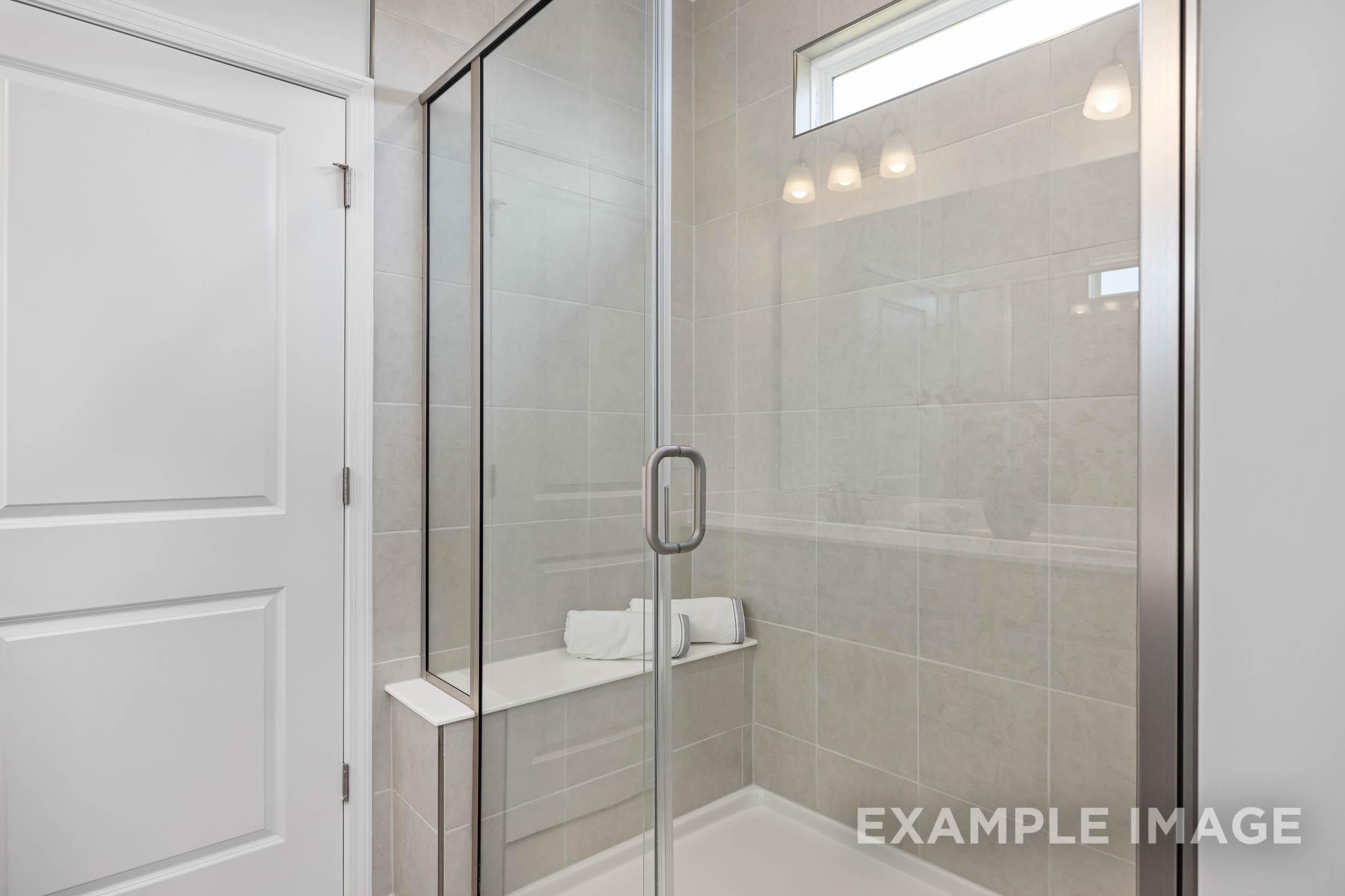 Modern master bathroom in The Daphne C featuring frameless glass shower, subway tile, and built-in bench