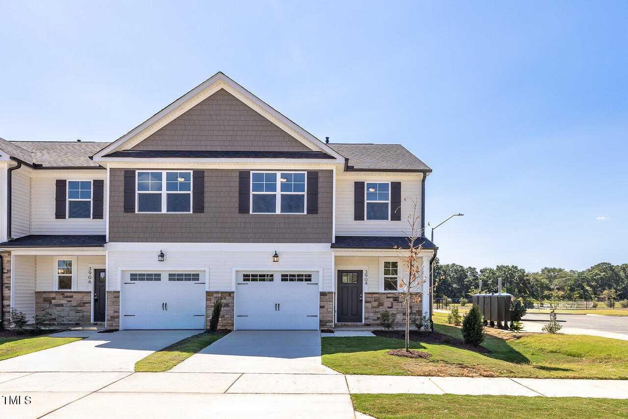 Modern two-story Graham Exterior townhome by Davidson Homes in Springvale, Fuquay-Varina, NC, featuring gray siding, white garage doors, and landscaped yard